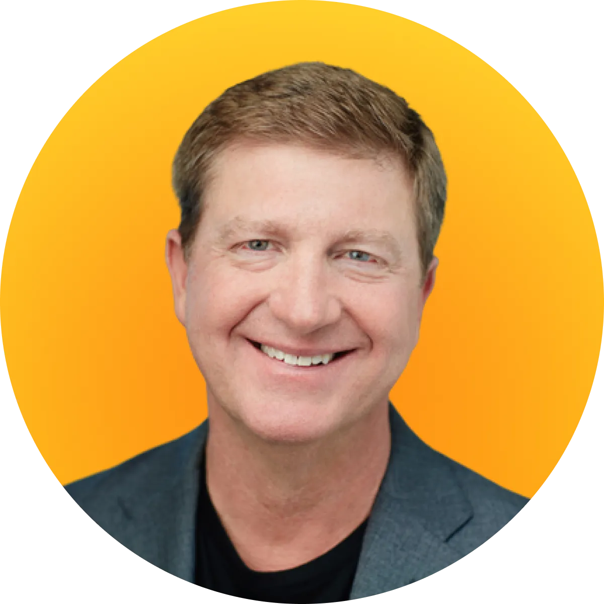 Smiling middle-aged man with light brown hair wearing a dark blazer and black shirt on orange background.