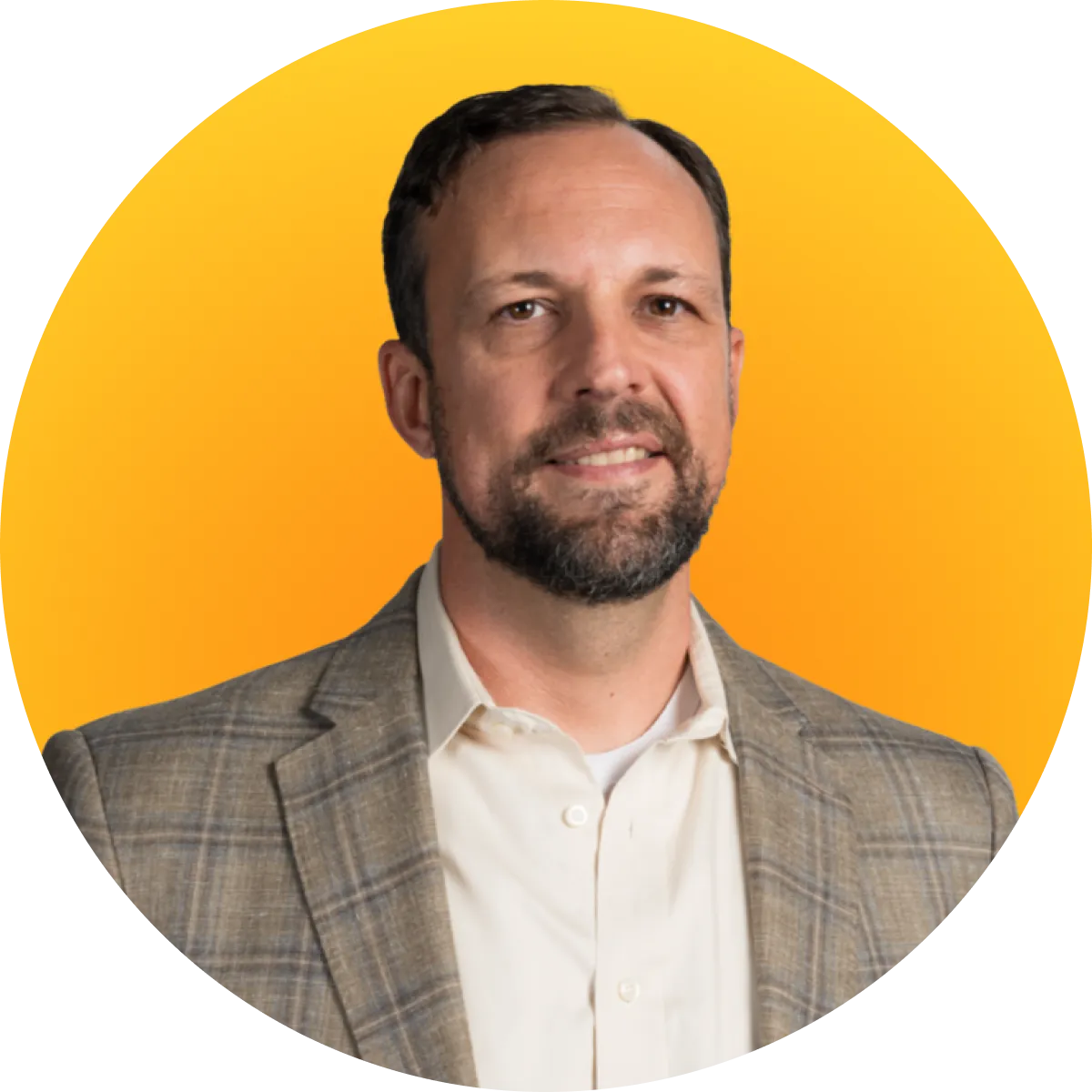 Man with short dark hair and beard wearing a beige plaid blazer and white shirt on yellow background.