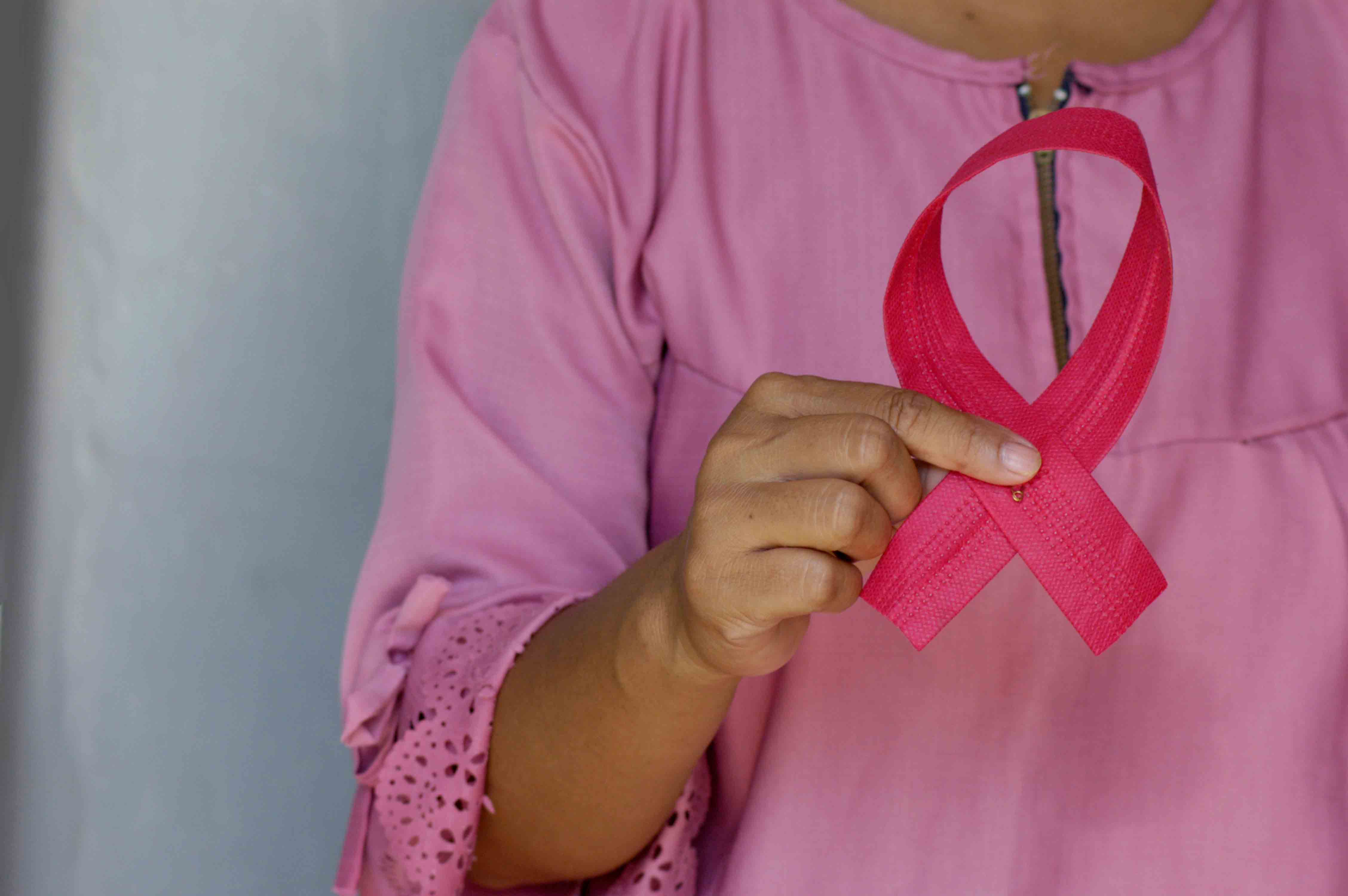 Breast cancer awareness and women with pink ribbon reflecting upon breast reconstruction