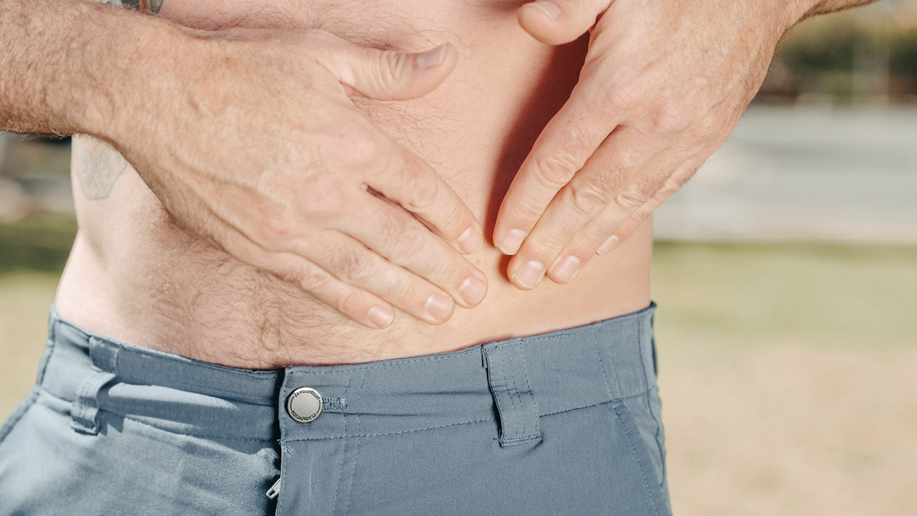 A man holds his lower abdomen in pain
