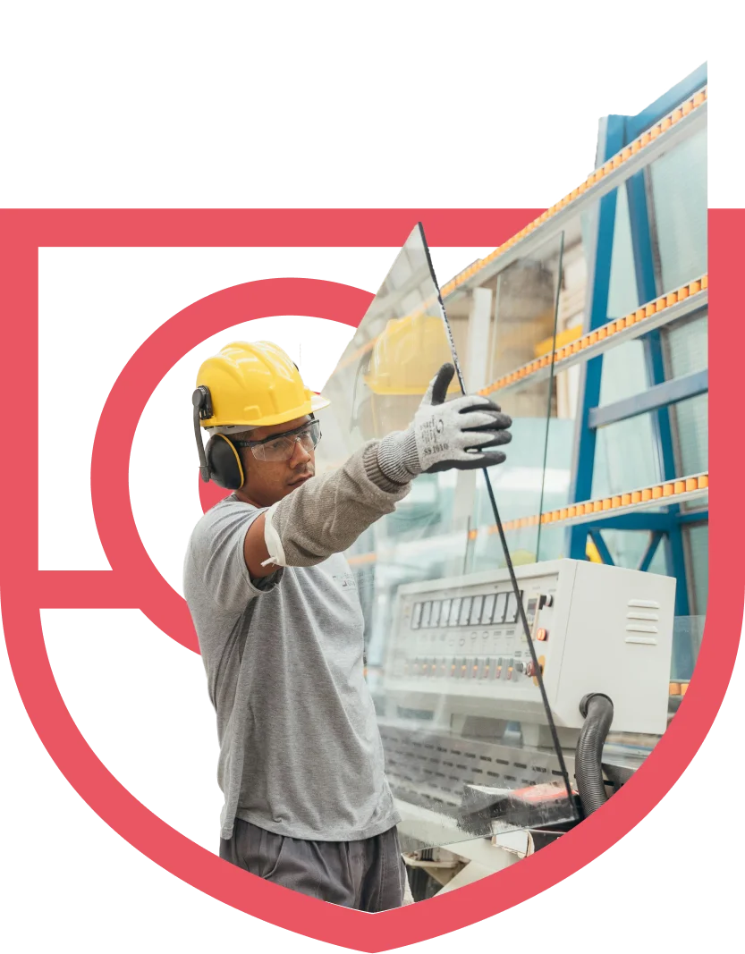 Factory worker handling a large glass panel in a plant