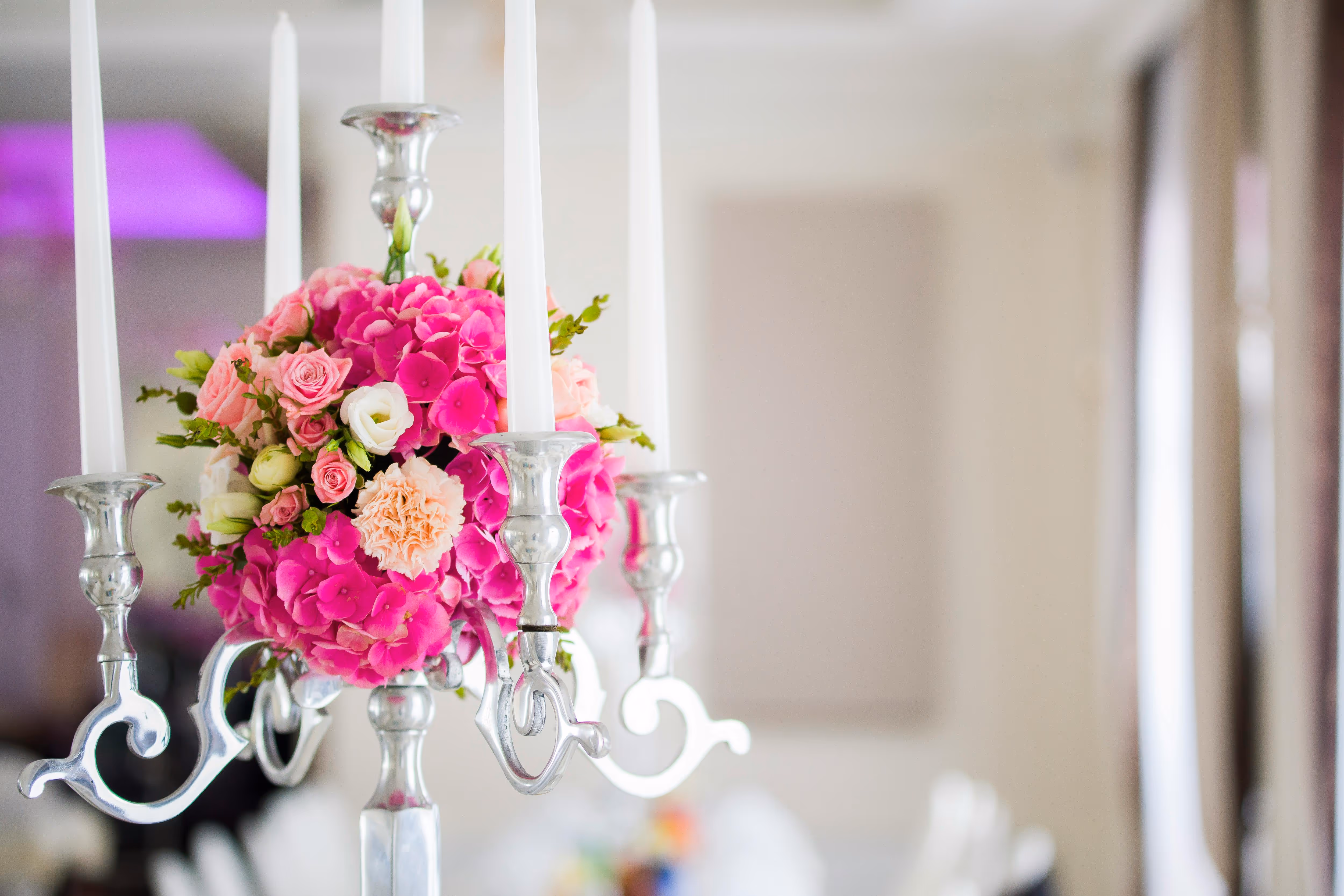 Silver candelabra centerpiece with white candles and pink roses and hydrangeas bouquet.