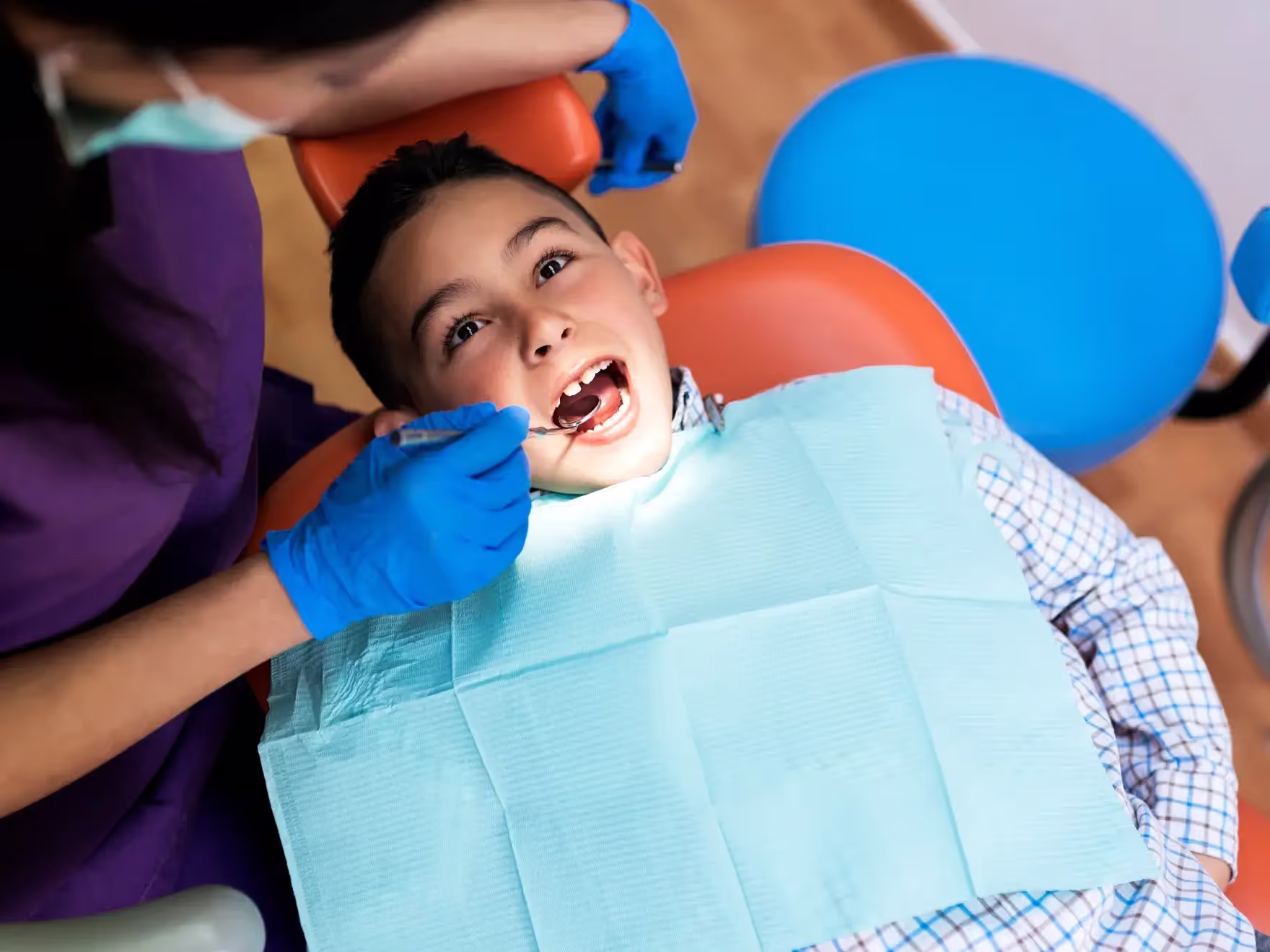 A young boy getting his teeth checked by a dentist.