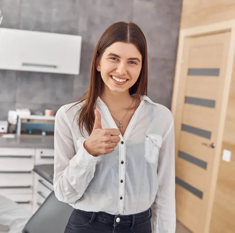A woman giving a thumbs up in a kitchen.