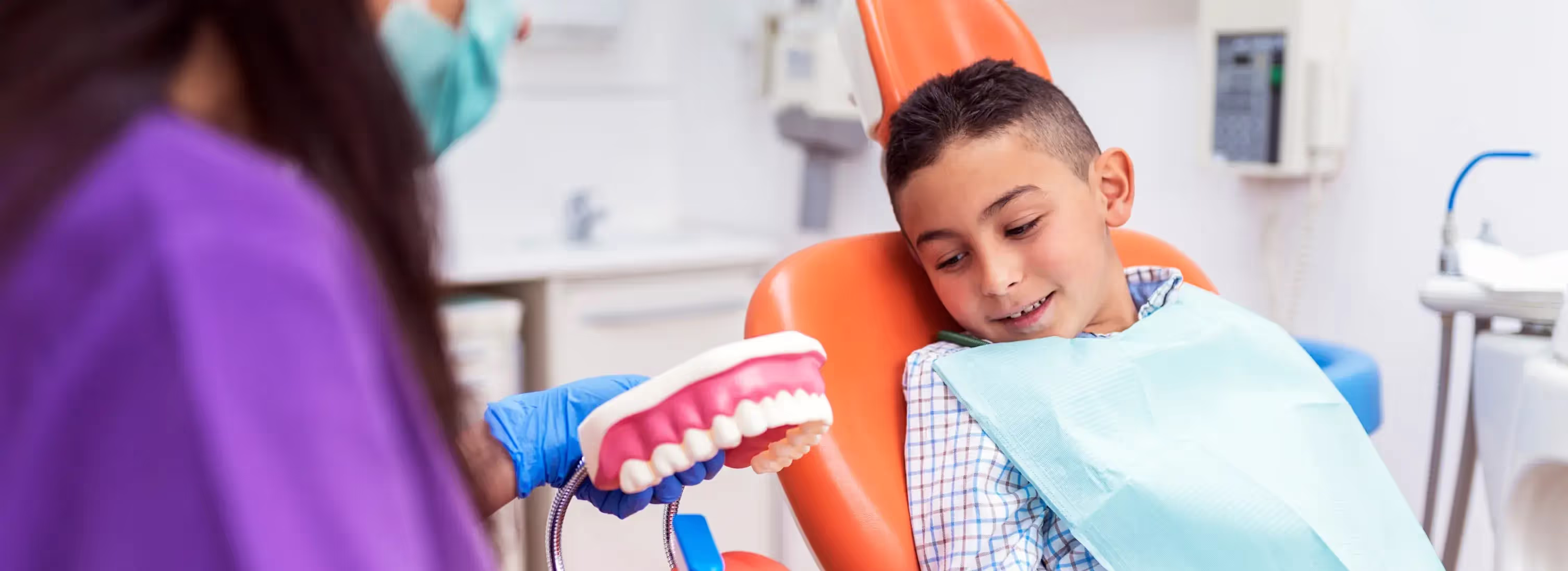 A young boy getting his teeth checked by a dentist.