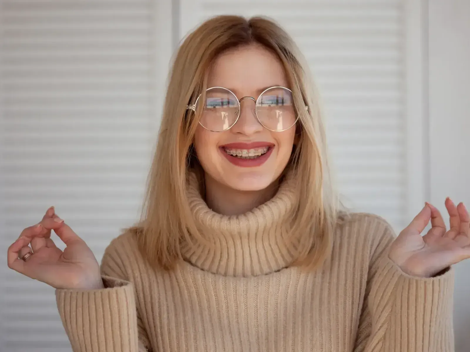 A woman wearing glasses and a turtle neck sweater.