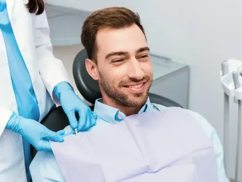 A man sitting in a dentist chair smiling at the camera.