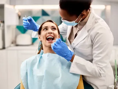 A woman getting her teeth brushed by a dentist.