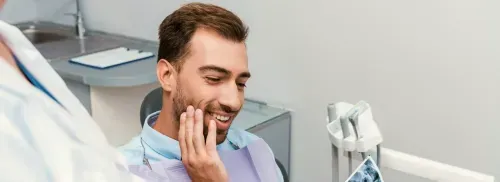 A man in a dentist chair smiling at another man.