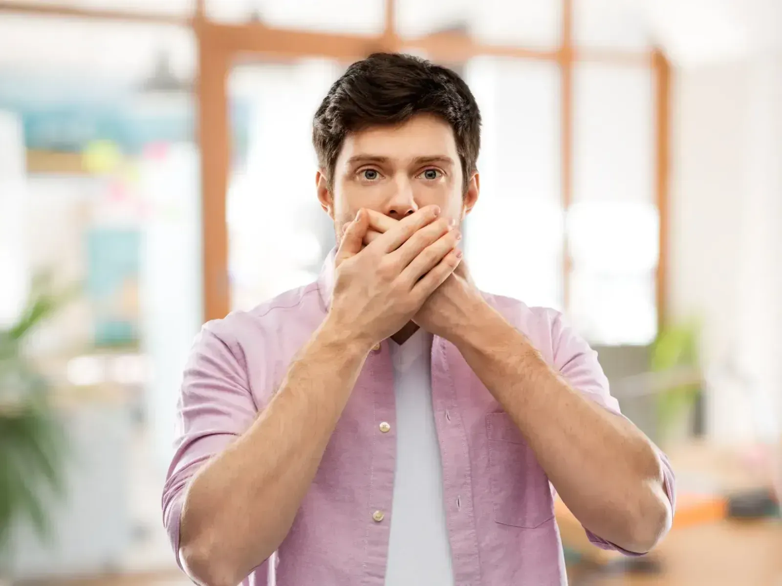 A man covers his mouth with his hands.