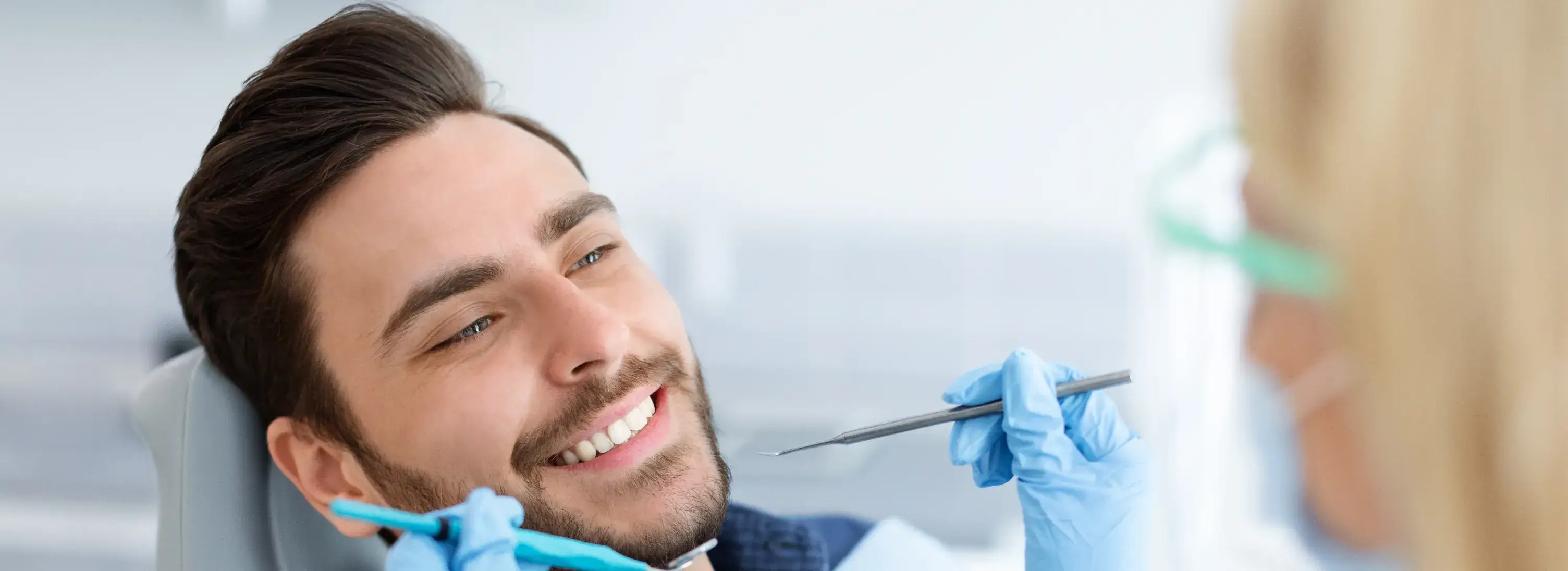 A man sitting in a dentist chair with a toothbrush in his mouth.