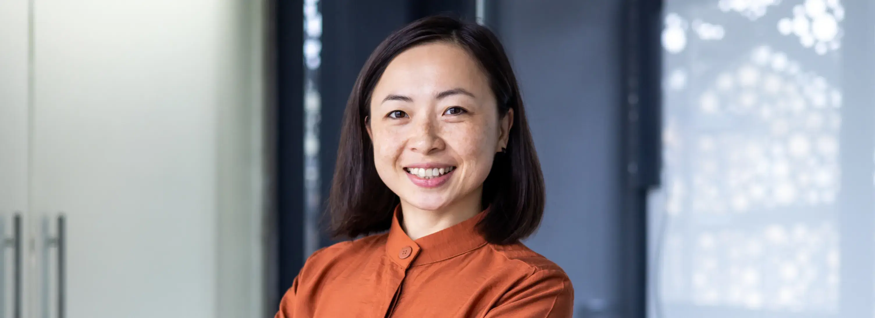 A woman in an orange shirt smiles at the camera.