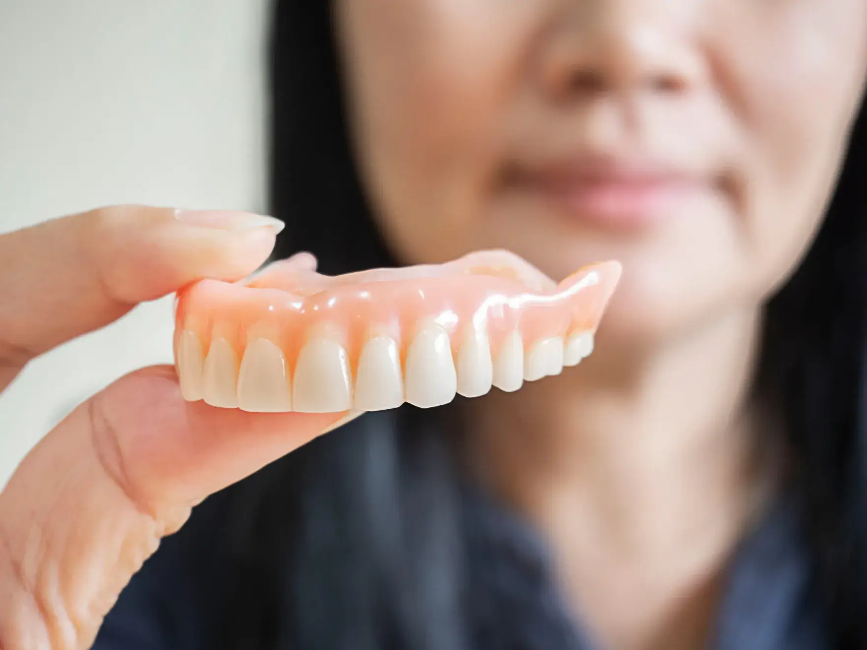 A woman holding a fake tooth in her hand.