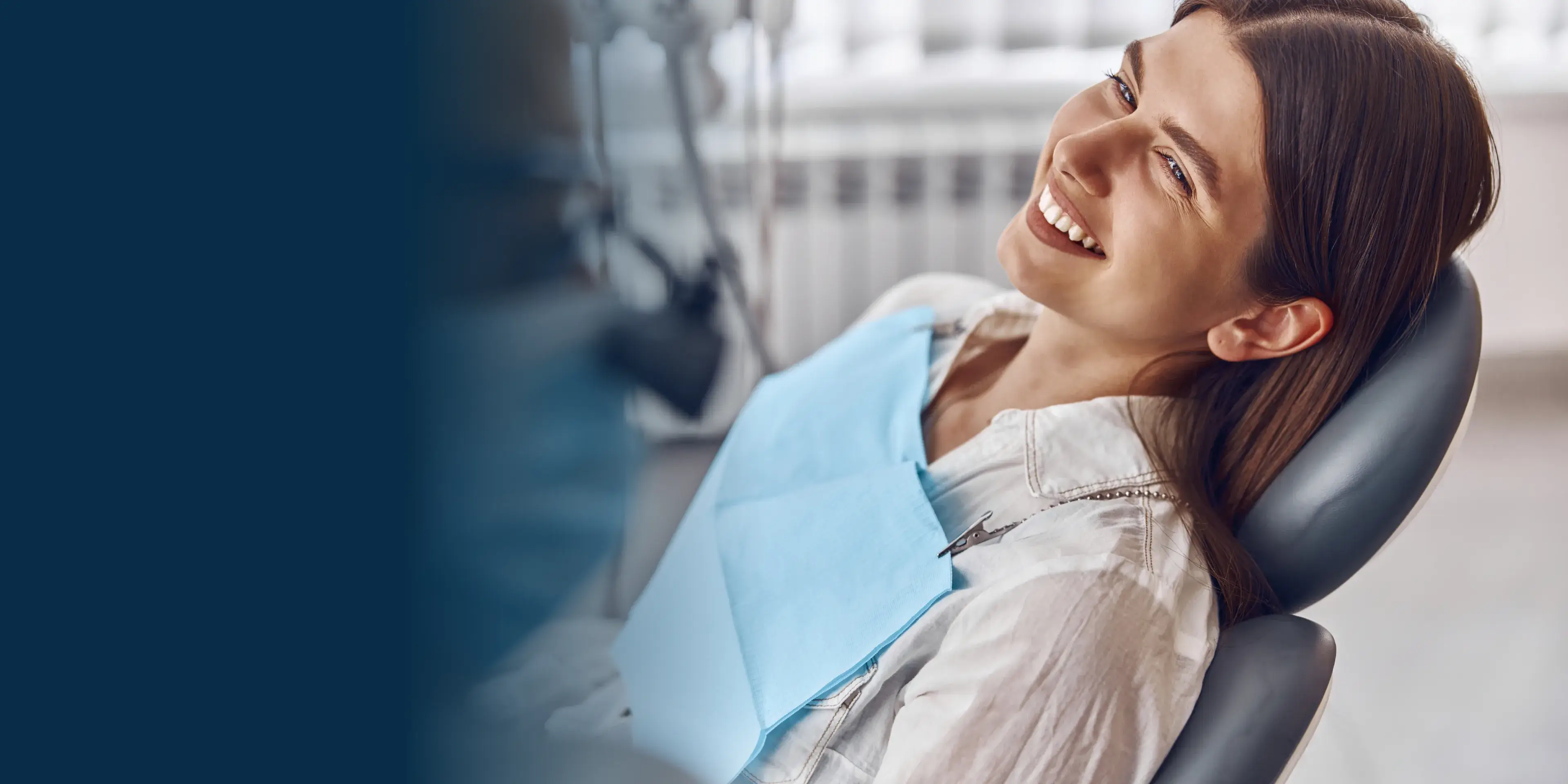 A woman sitting in a dentist chair smiling.
