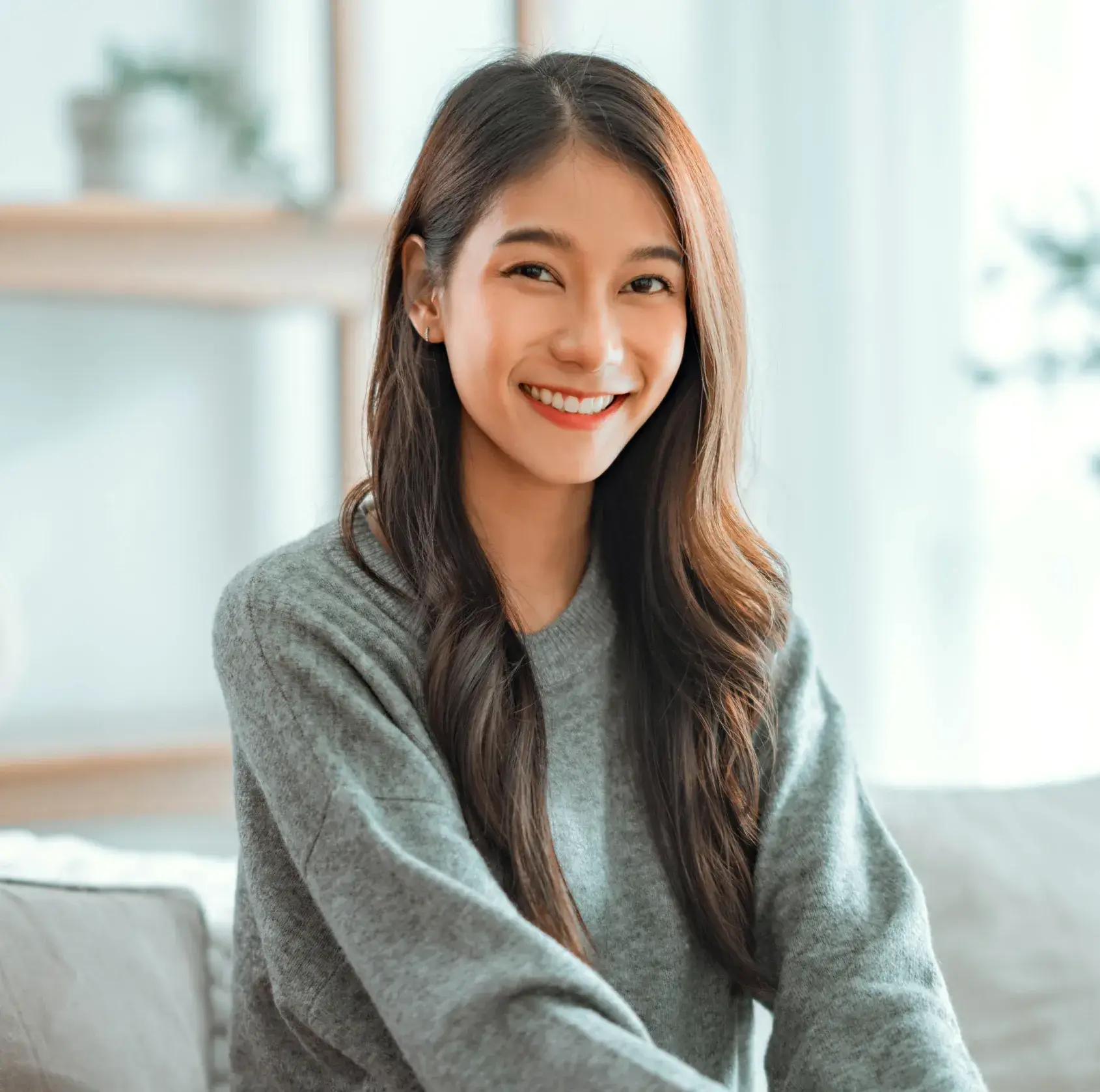 A woman sitting on a couch smiling at the camera.