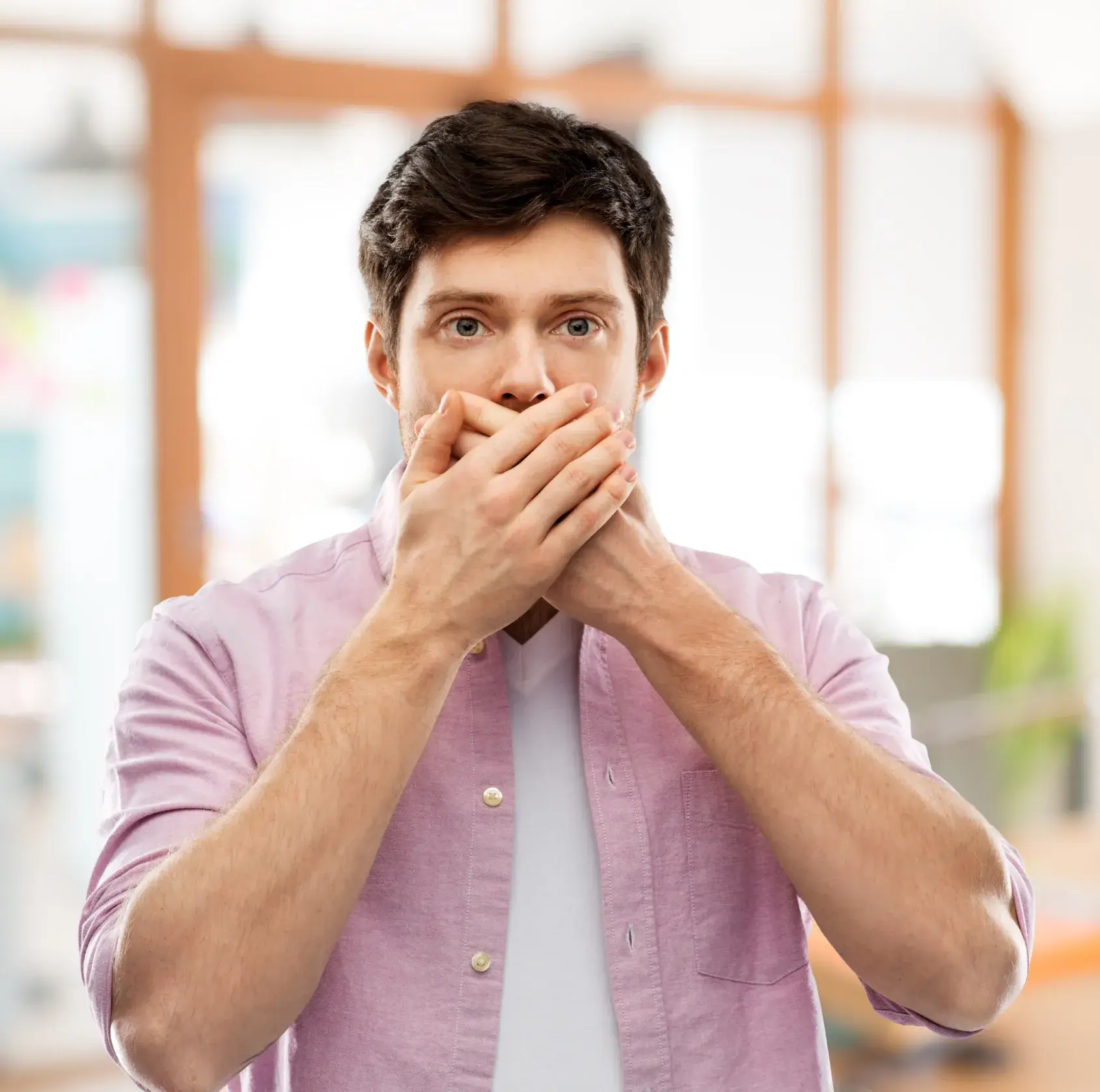 A man covers his mouth with his hands.