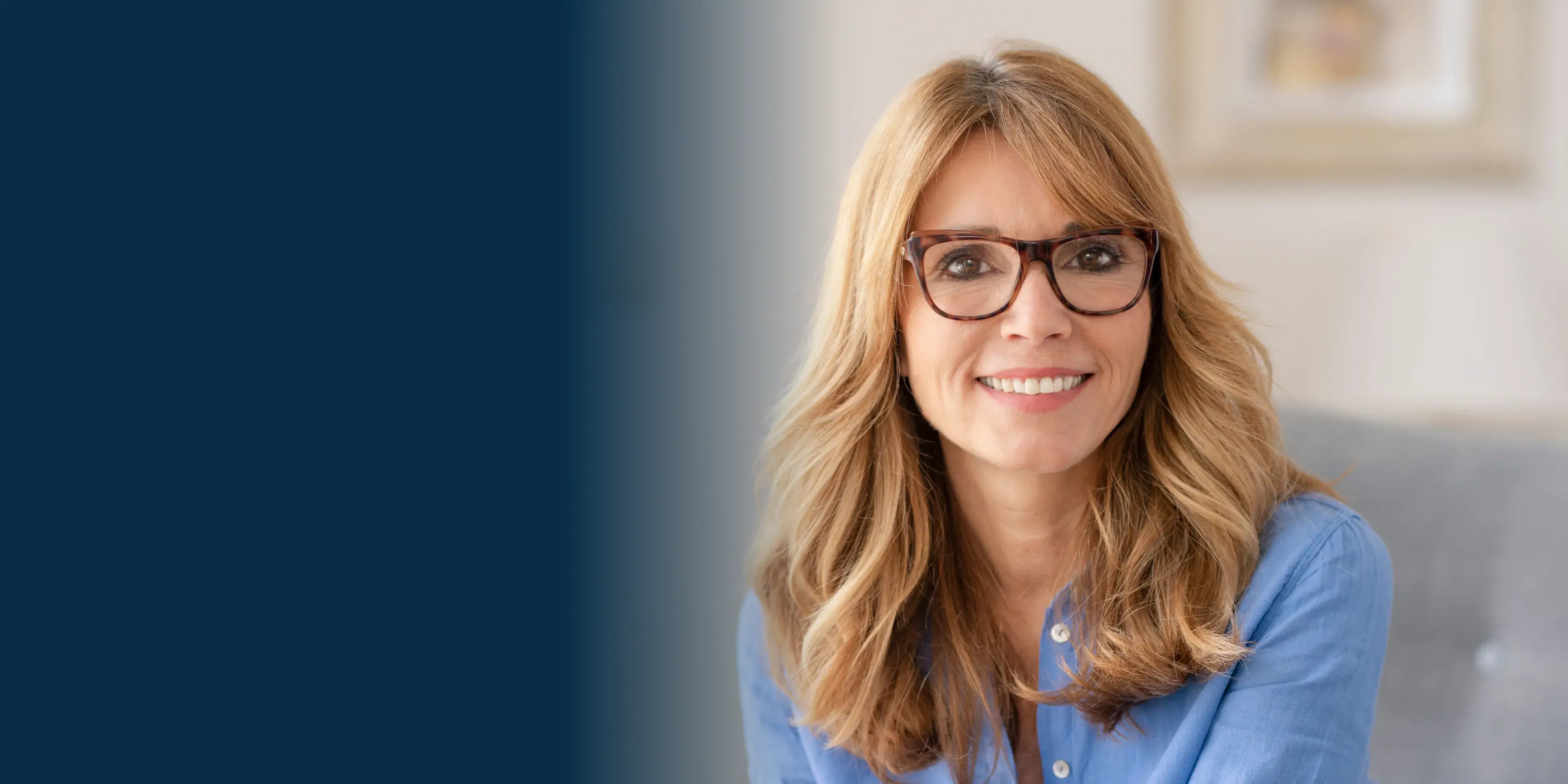 A woman wearing glasses sitting on a couch.