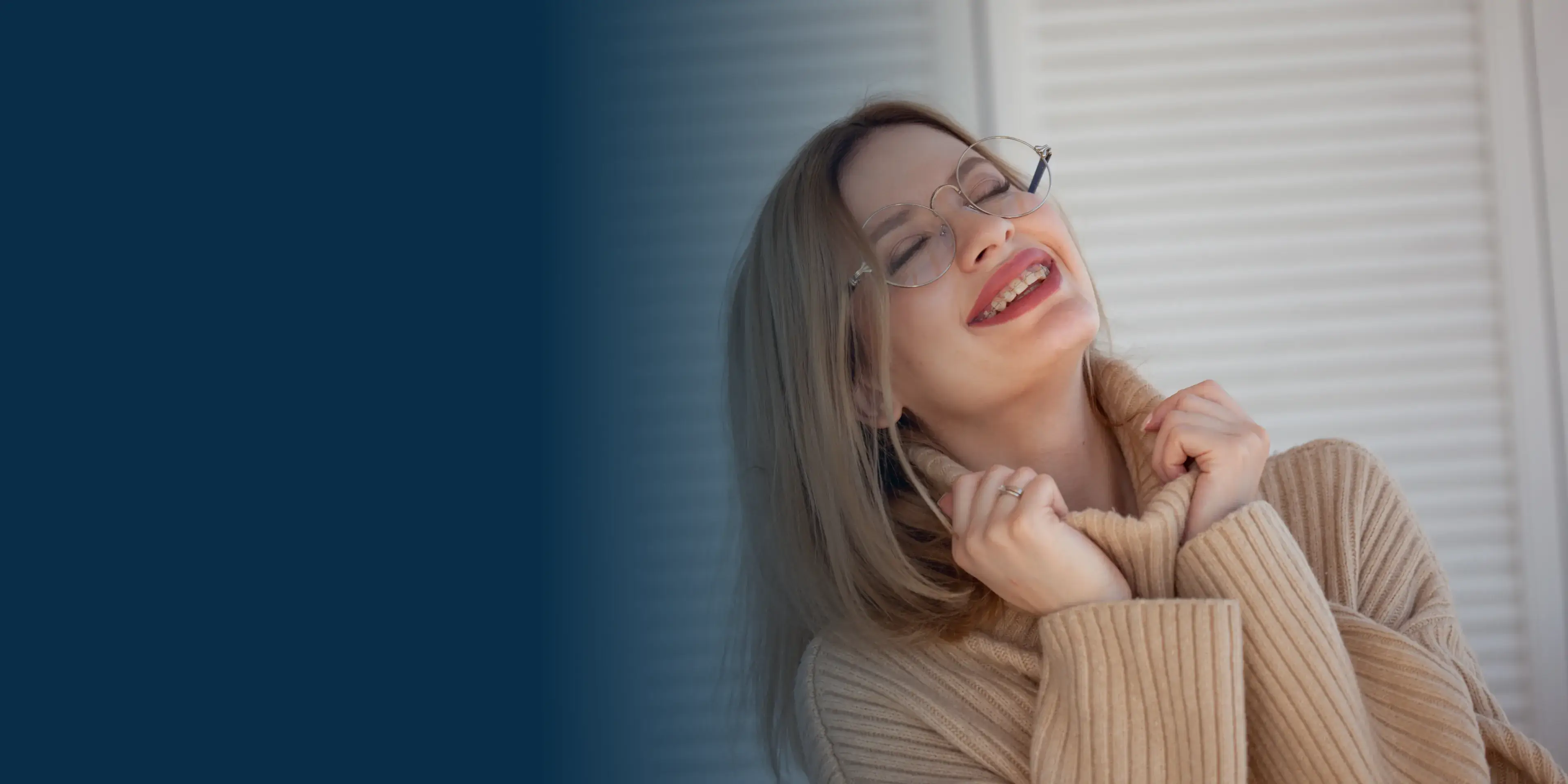 A woman wearing glasses and a tan sweater.