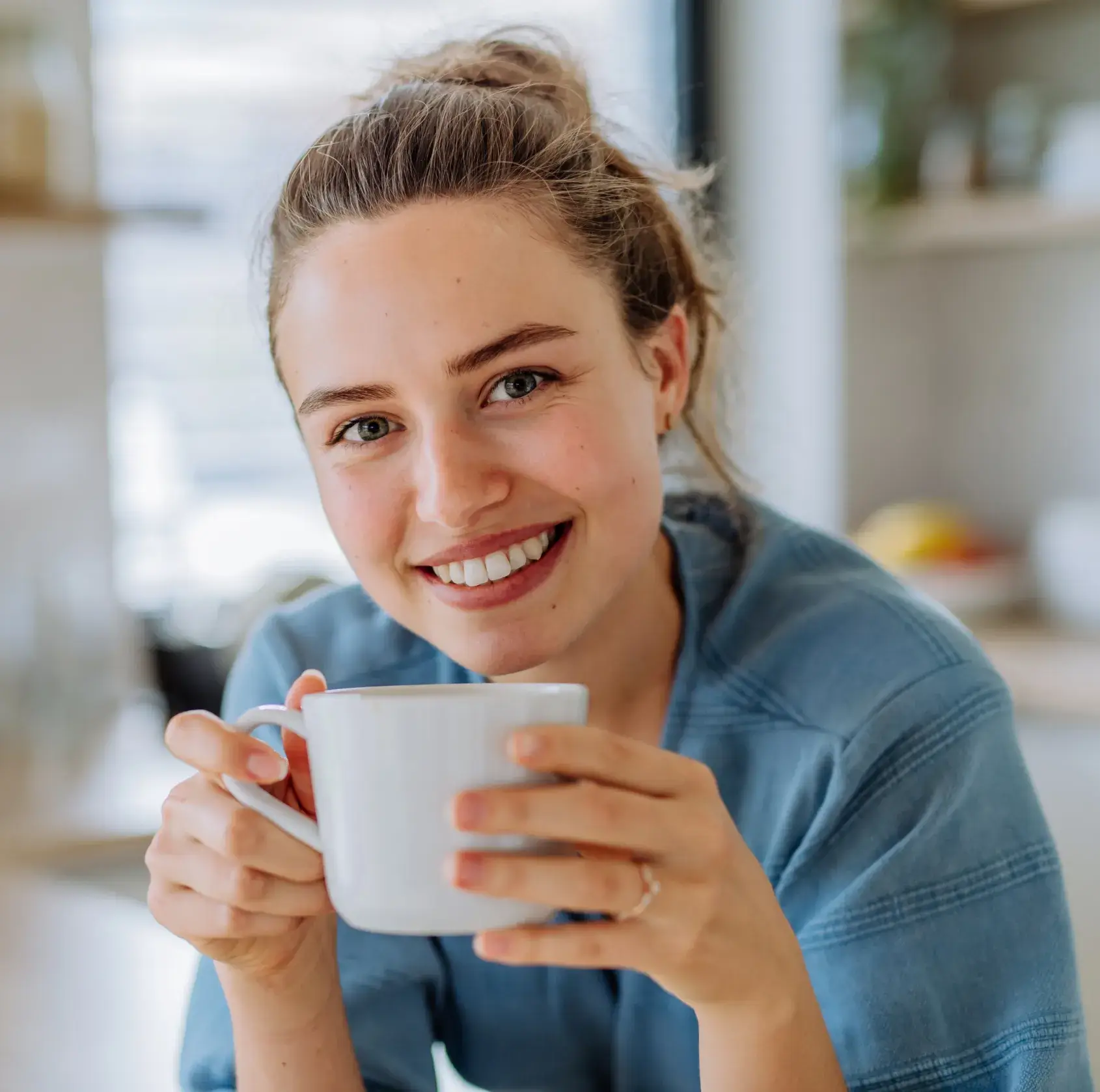 A smiling woman holding a cup of coffee.