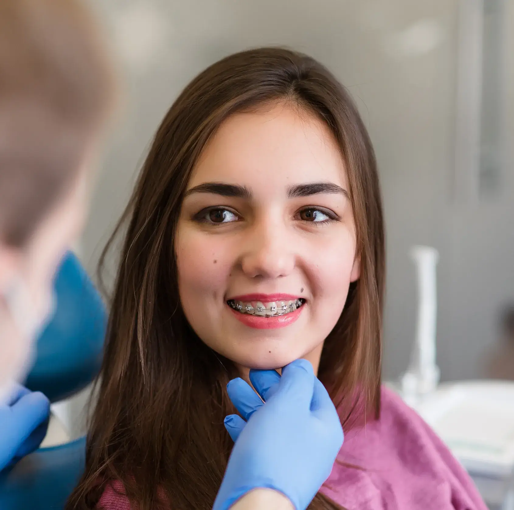 A woman getting her teeth brushed by a dentist.