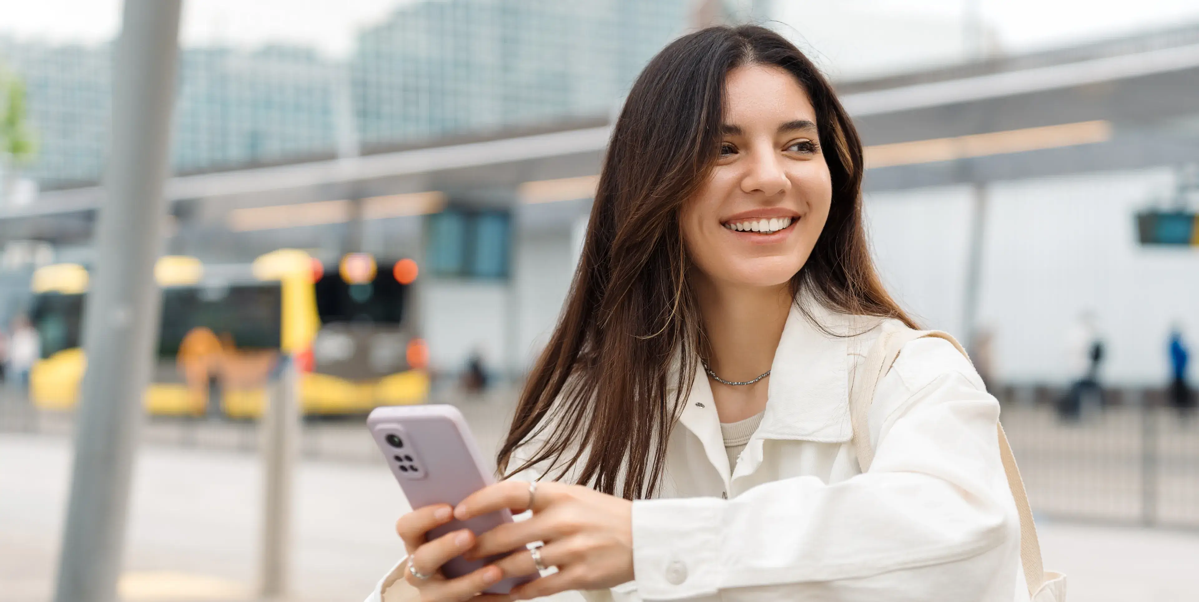 A woman smiles while holding a cell phone.