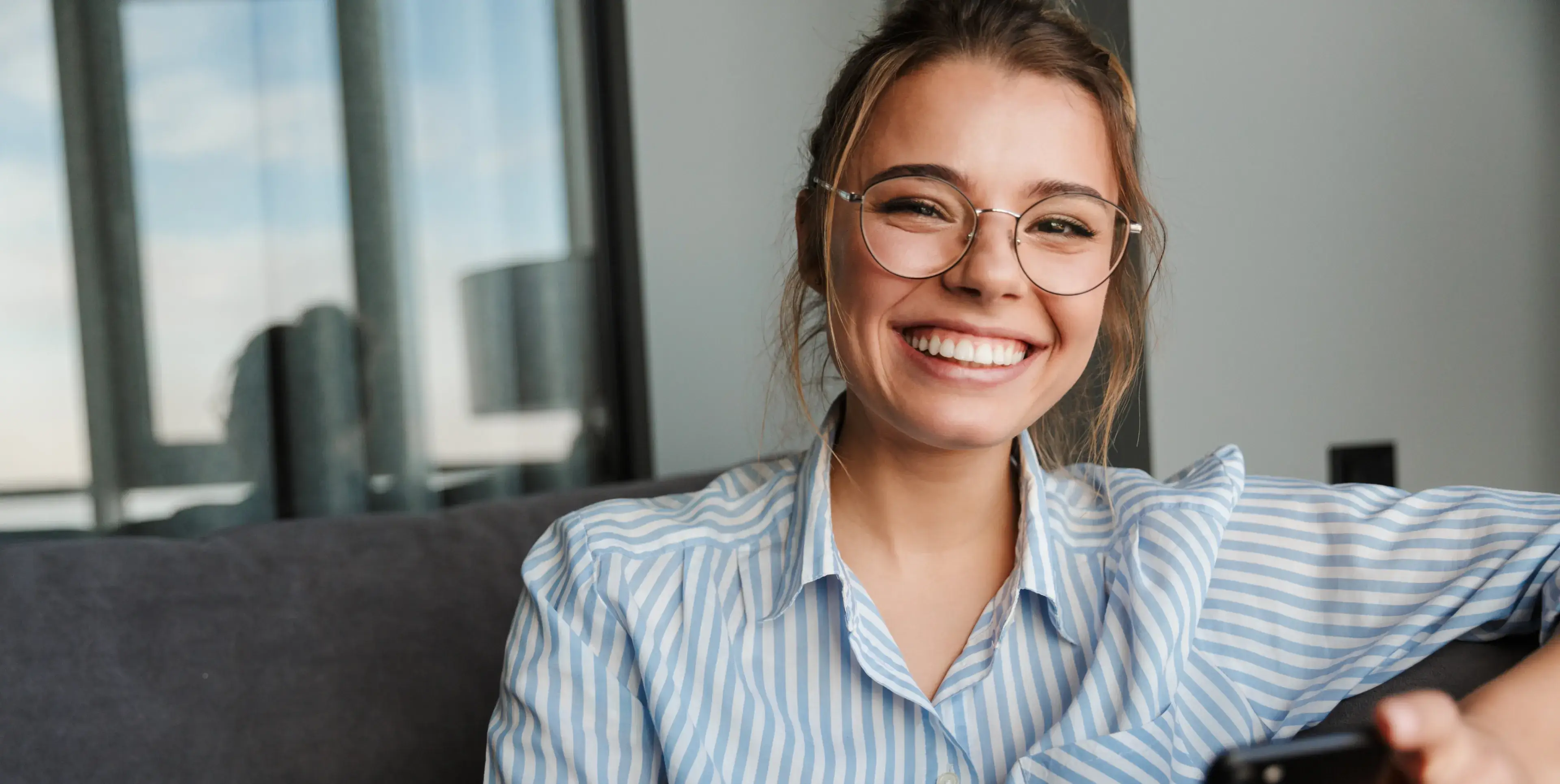 A woman wearing glasses holding a remote control.