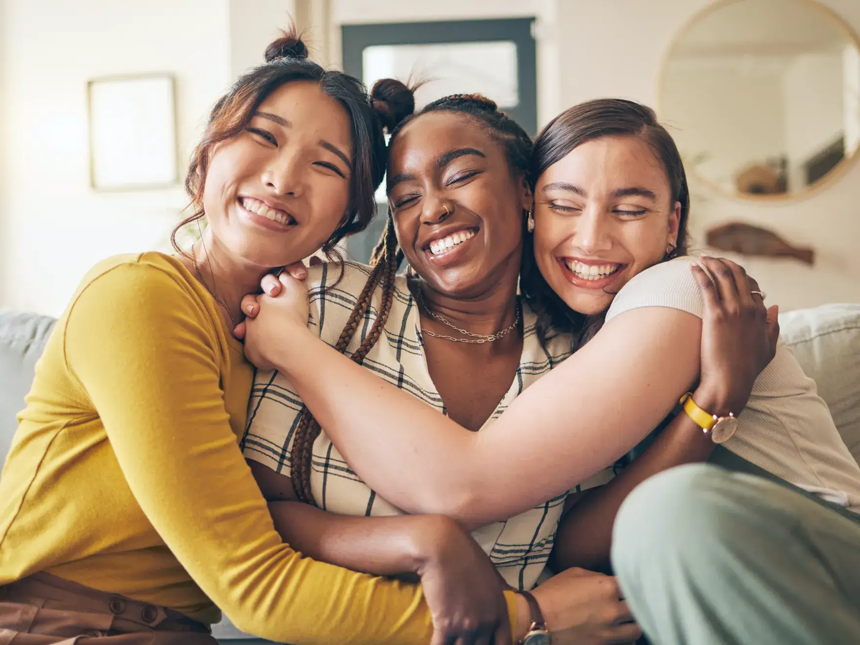A group of women hugging each other on a couch.