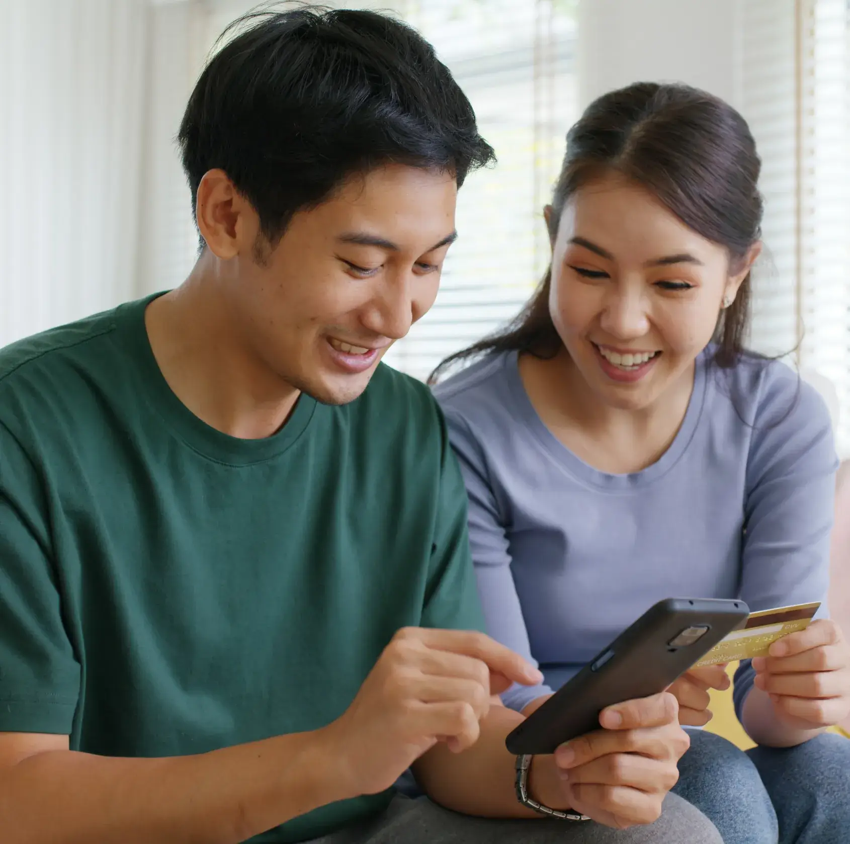 A man and woman sitting on a couch looking at a tablet.