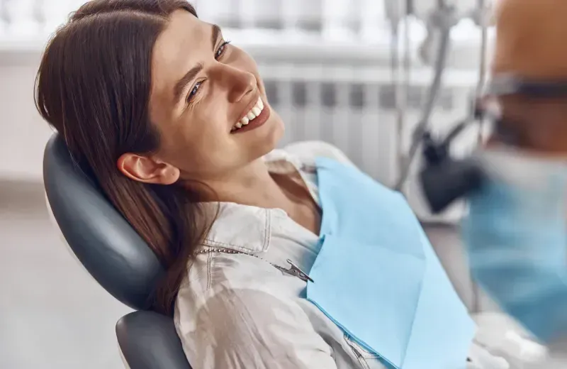 A woman sitting in a dentist chair smiling.