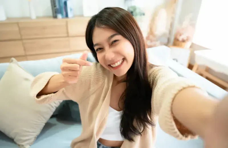 A woman giving a thumbs up sign in a living room.