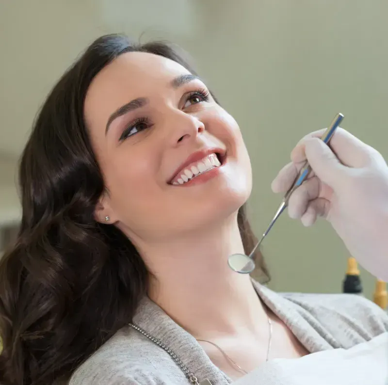 A woman getting her teeth brushed by a dentist.