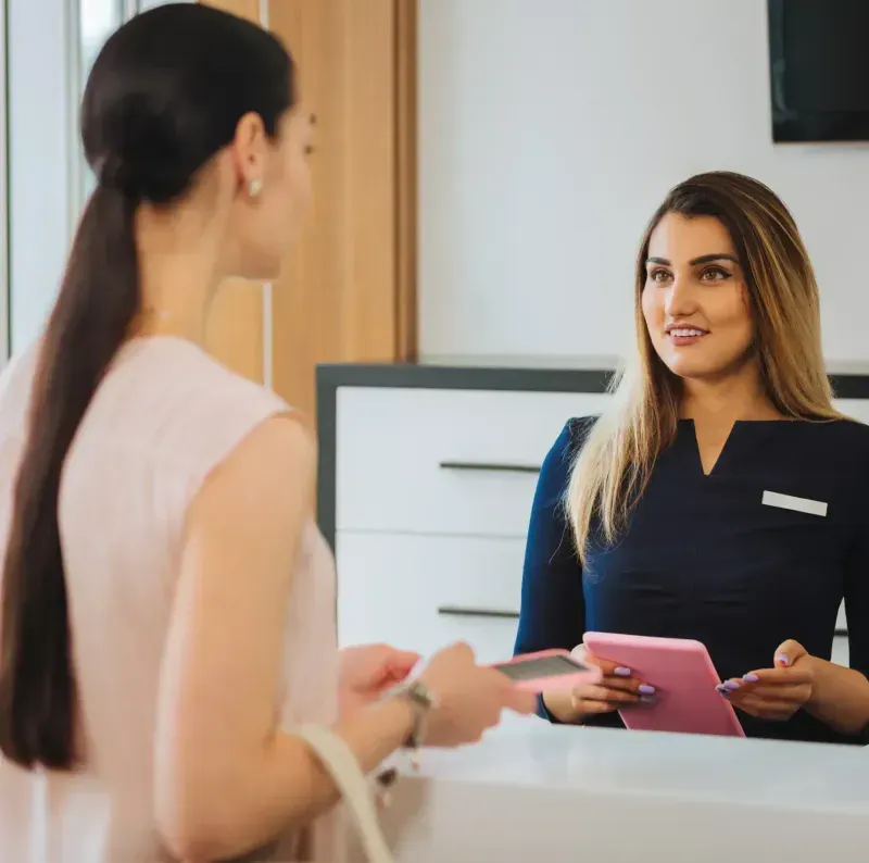 A woman standing in front of a counter talking to another woman.