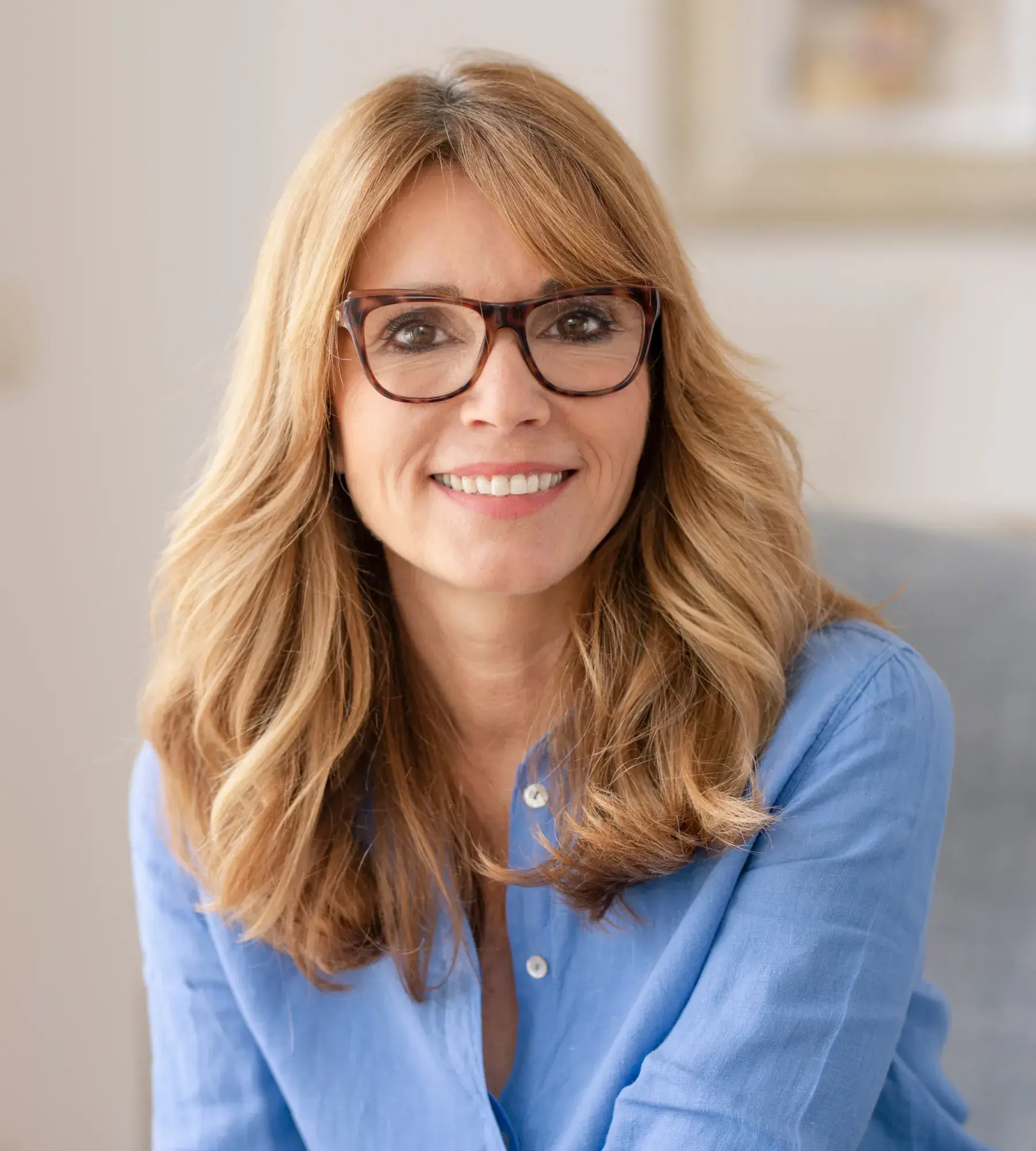 A woman wearing glasses sitting on a couch.