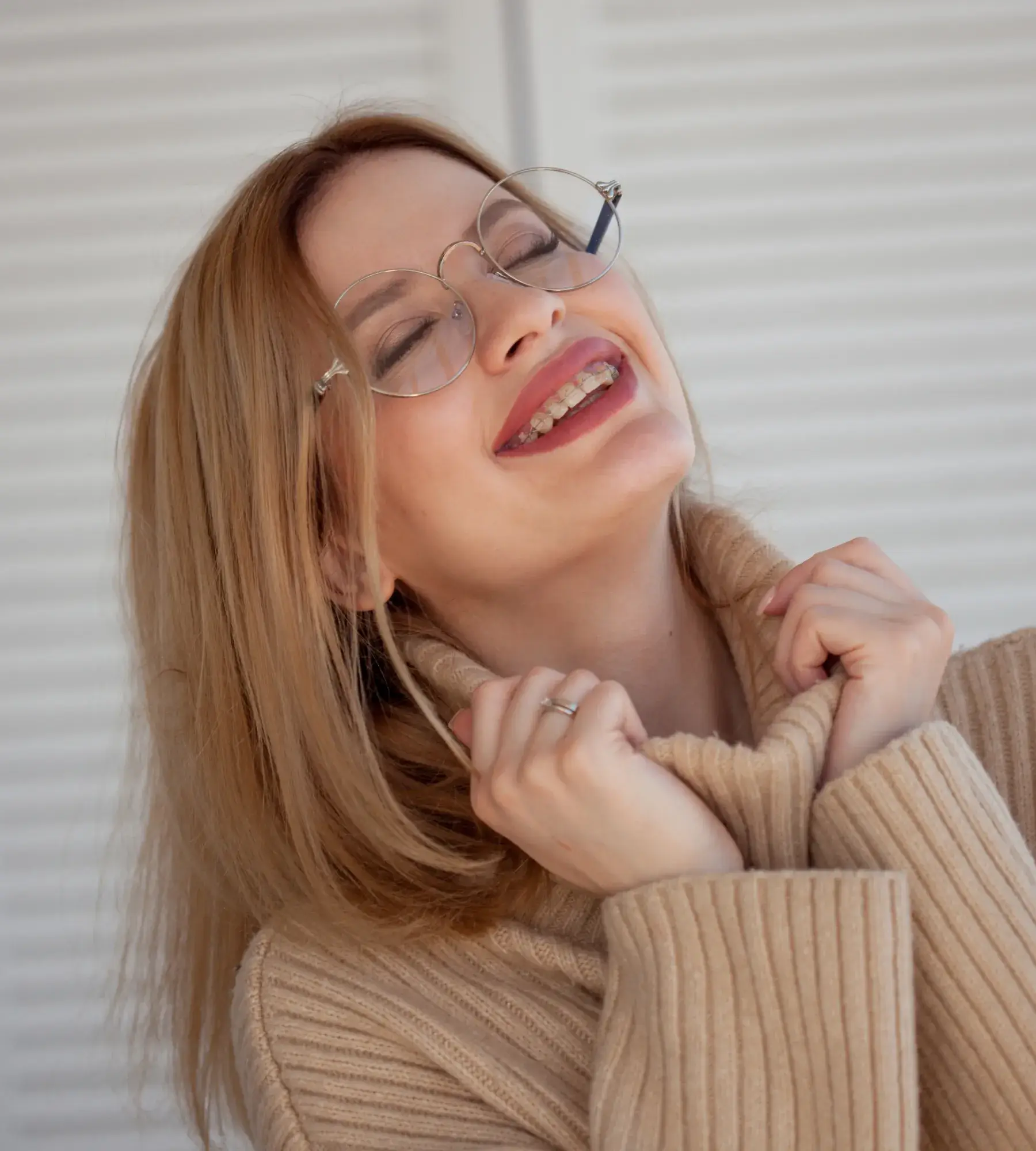 A woman with glasses smiling and wearing a sweater.