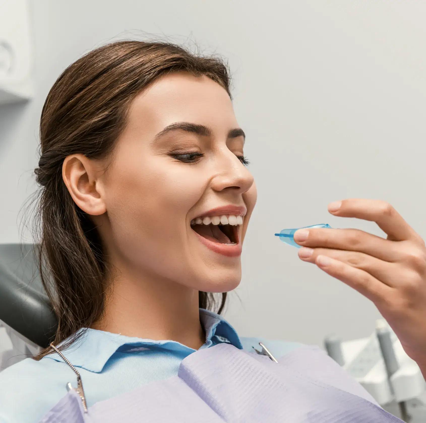 A woman in a dentist chair with a toothbrush in her mouth.