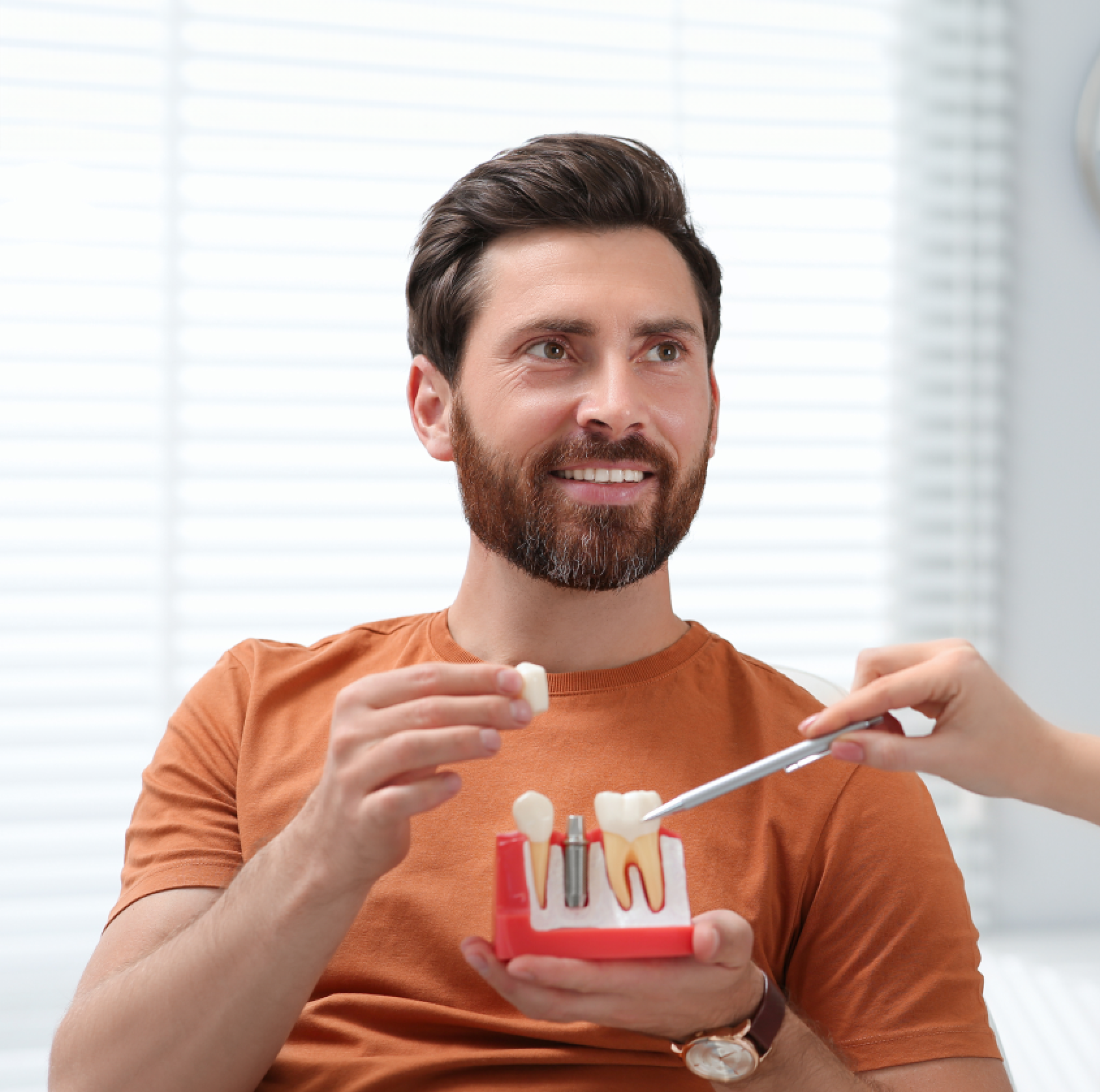 there is a man holding a toothbrush and a tooth model Dental Implants Smile Dental Studio