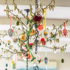 Colorful decorative eggs hanging from branches indoors as spring or Easter decor.