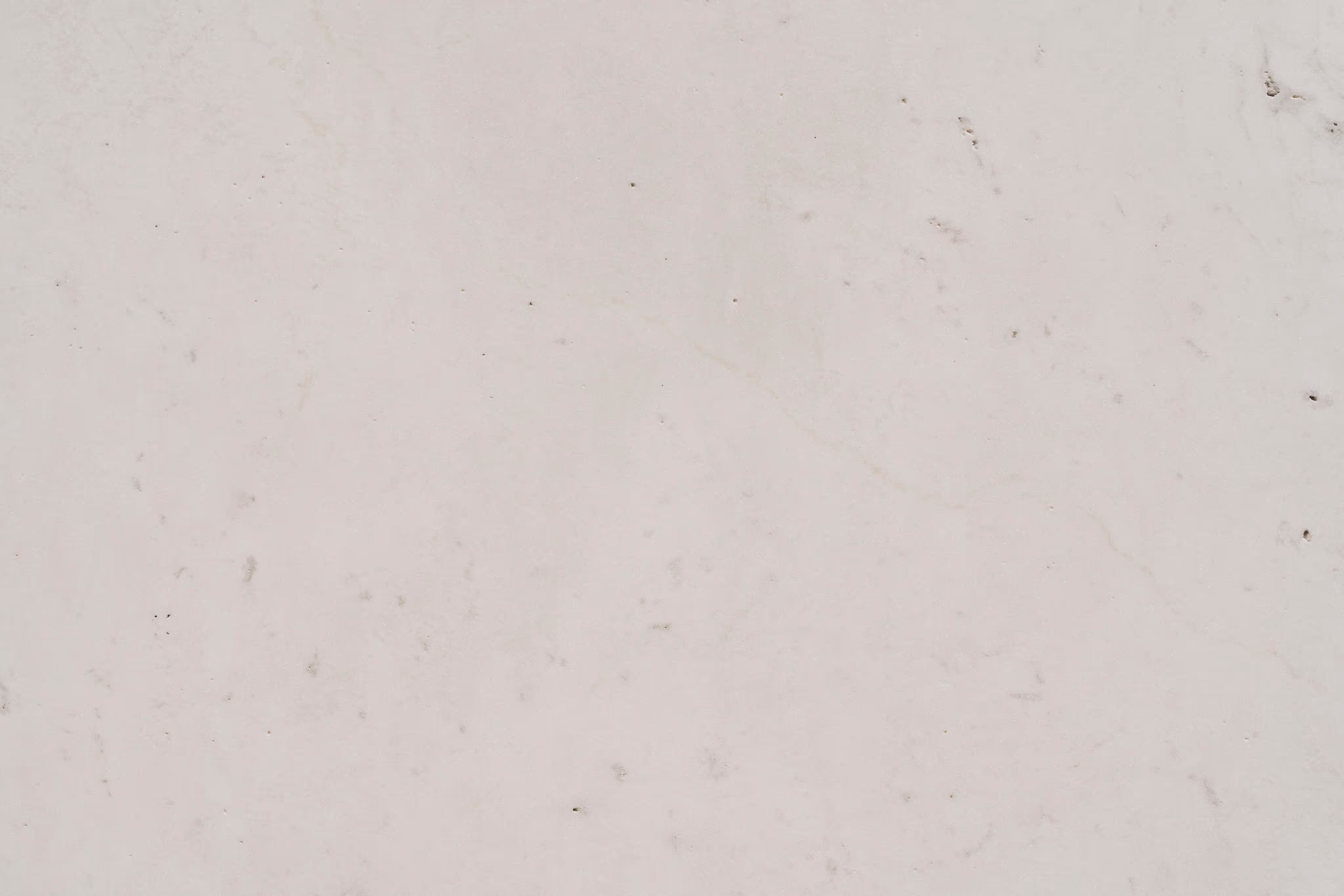 Close-up of a light grey marble surface with subtle veining and small dark speckles.