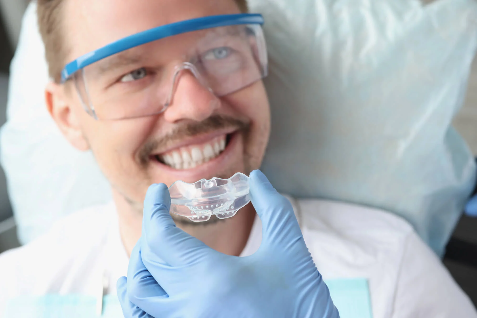 man smiling while getting his mouthguard at the dentist