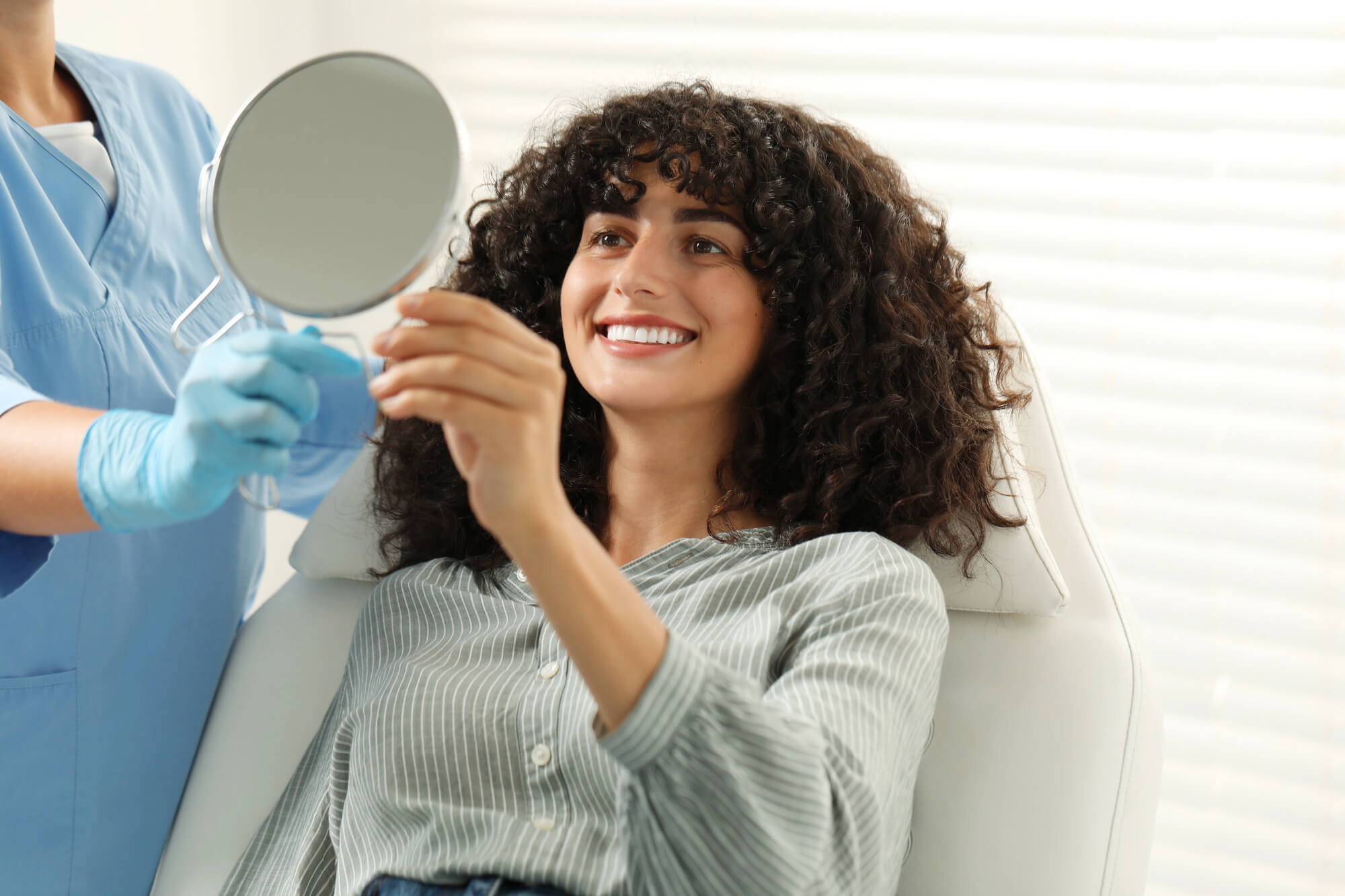 woman looking at her smile in the mirror