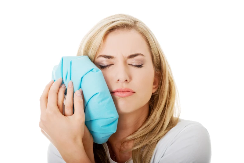 woman with dental pain has a cold pad on her face