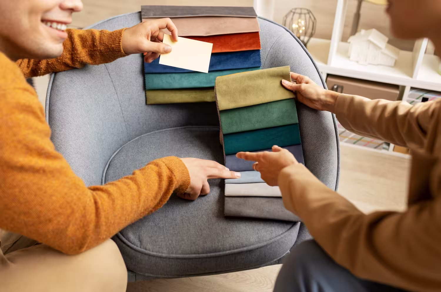 Two people comparing coloured fabric swatches for window treatments during a design consultation