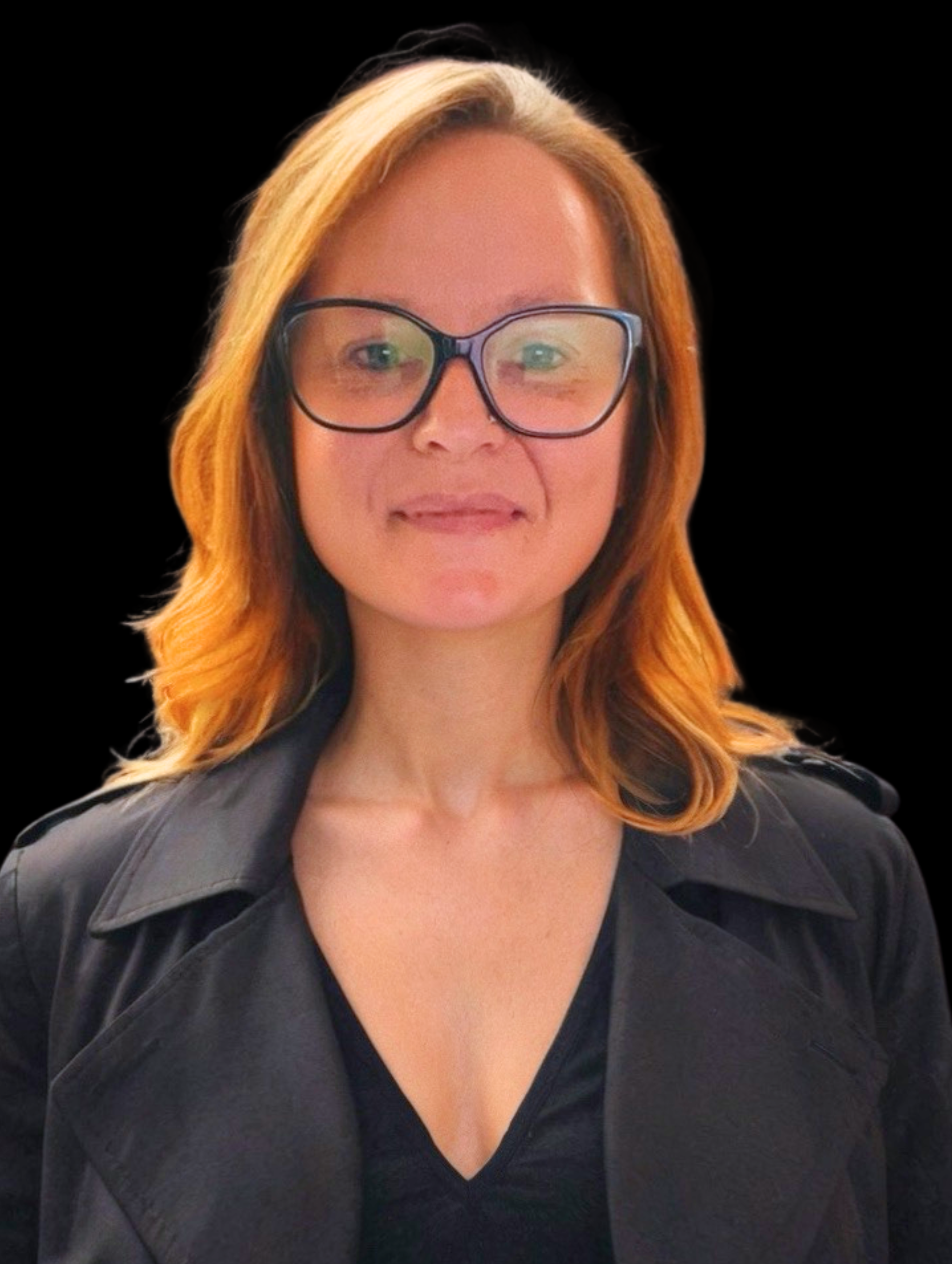 Smiling woman with glasses, long light brown hair, wearing a white blazer and black top, against a black background.