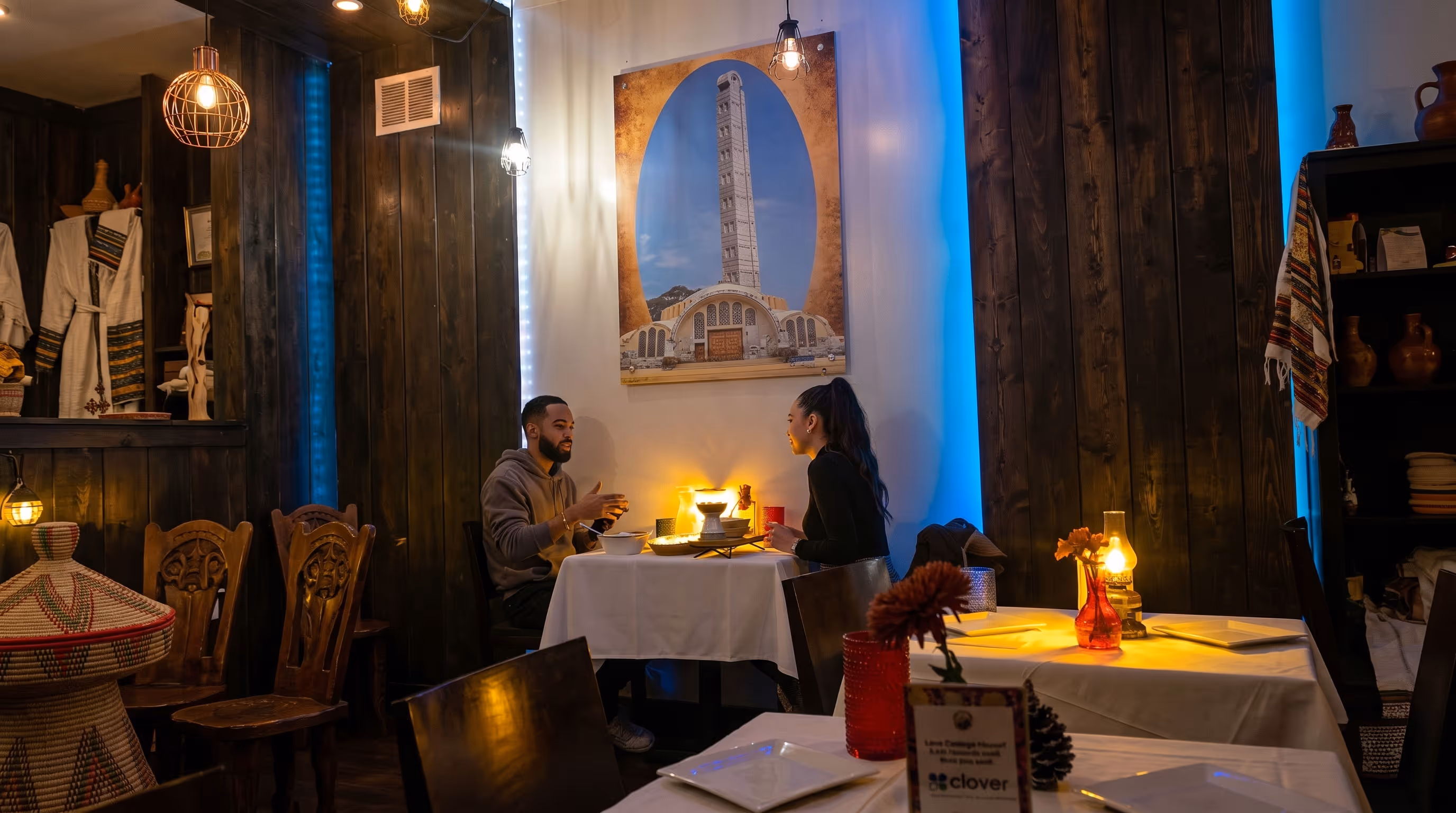 Couple seated at a small table in a cozy dimly lit restaurant with wooden walls and traditional decor.