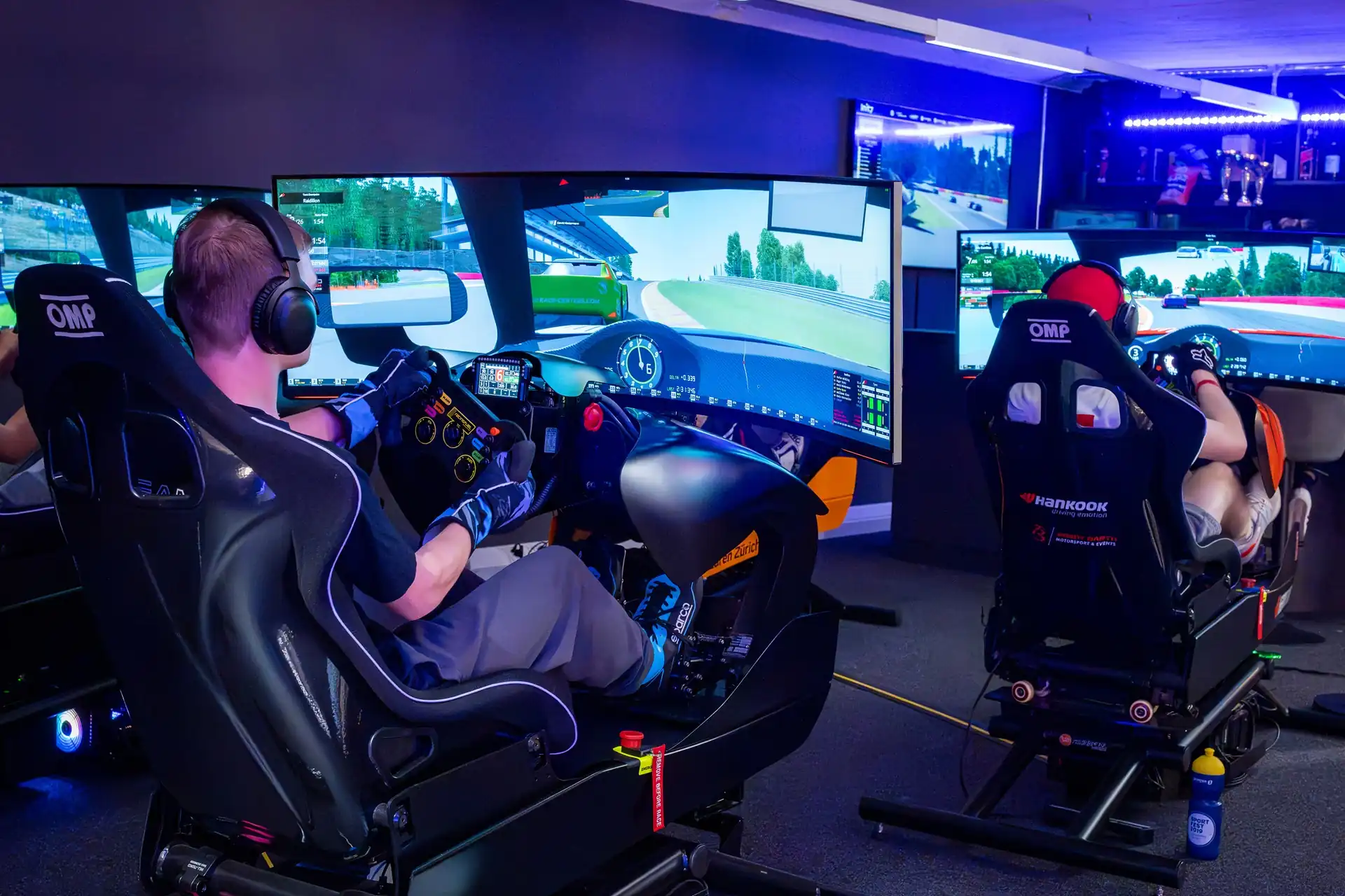 Zwei Männer sitzen in High-End-Rennsimulatoren und fahren gegeneinander auf der virtuellen Rennstrecke.