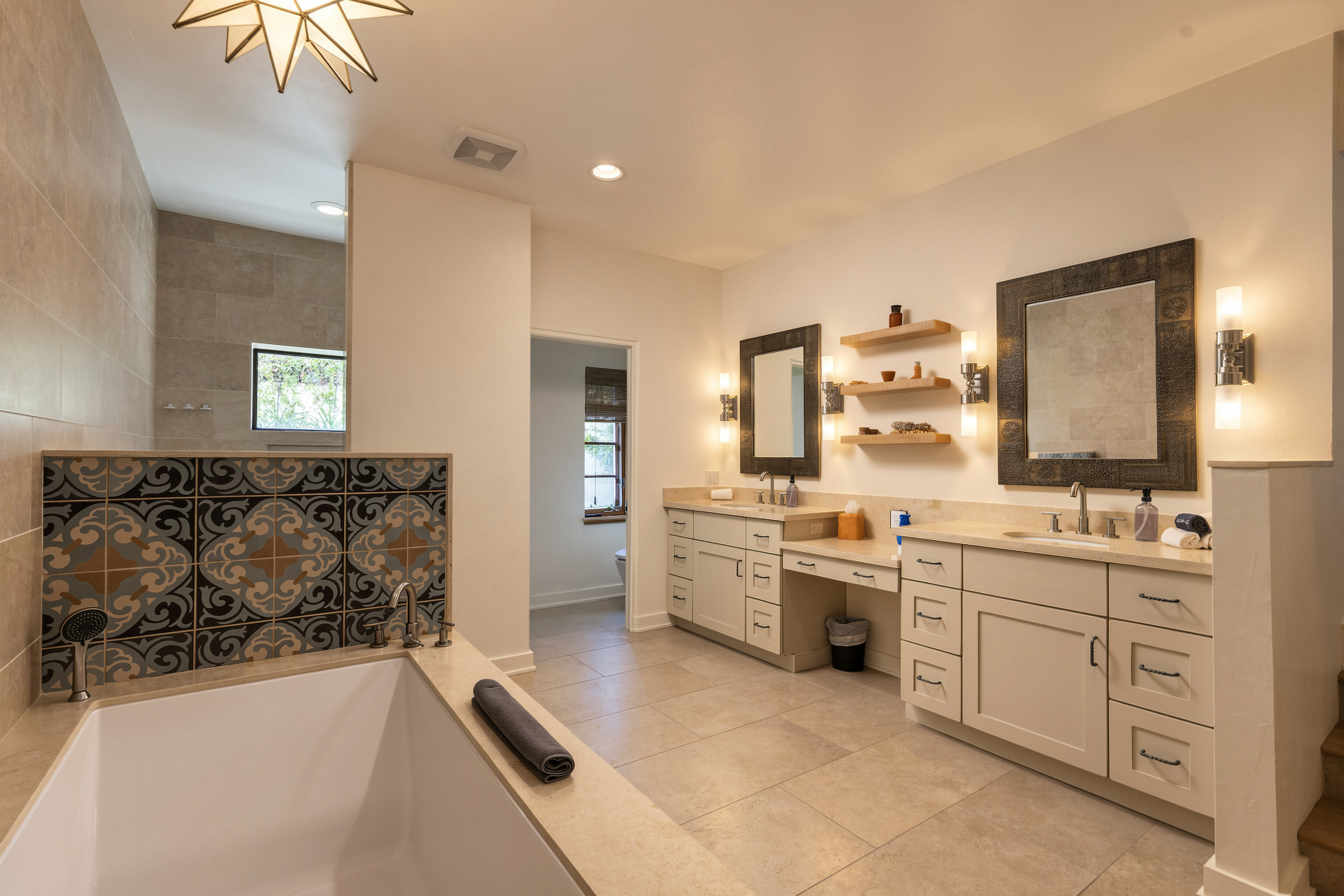 Bathroom with a patterned tile tub surround and dual vanities, shown with warm, moody photo editing.