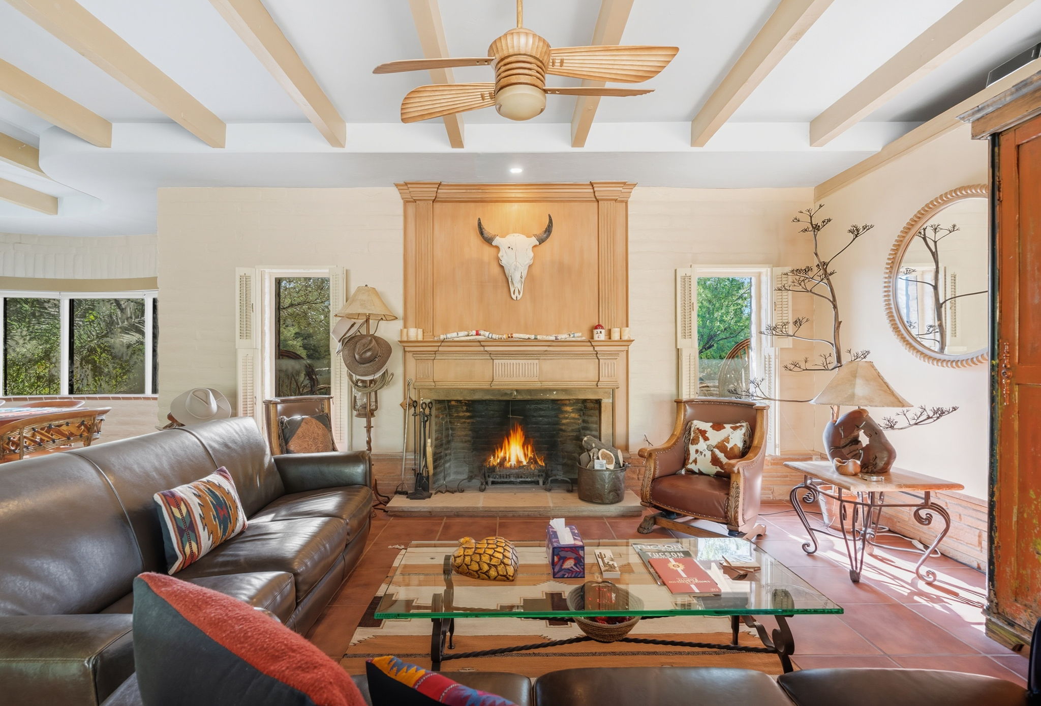 Southwestern living room with a fireplace, wood beams, and leather seating.