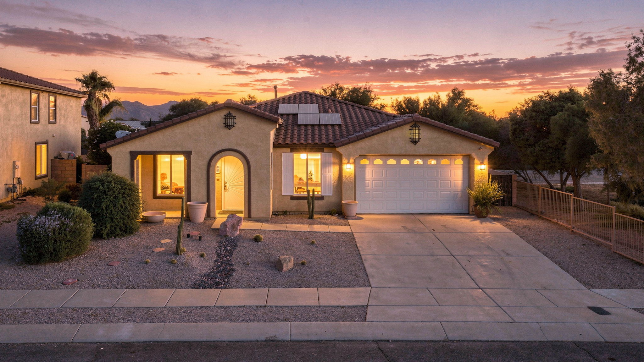 Single-story home beneath orange and pink sunset clouds
