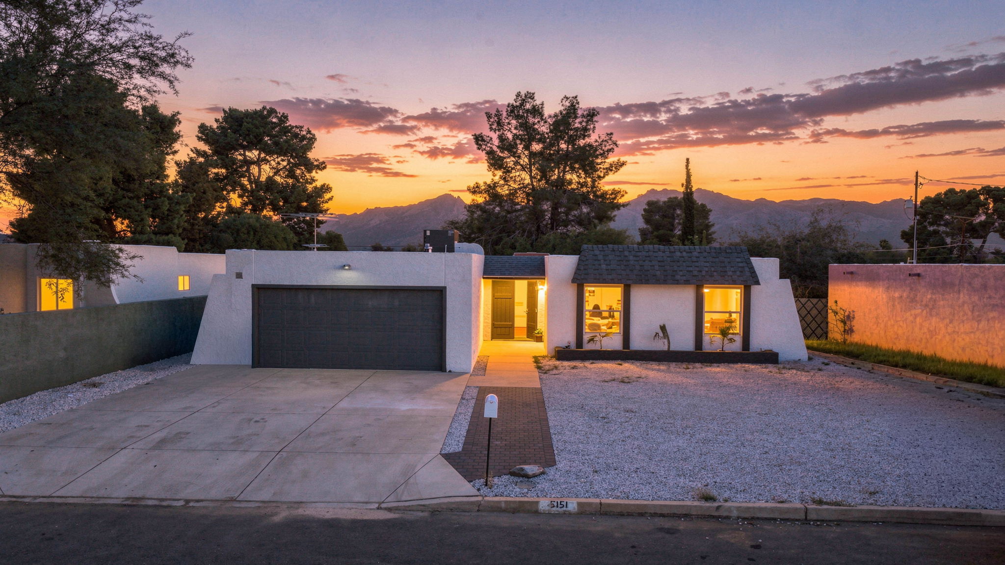 White single-story home with warm windows at dusk