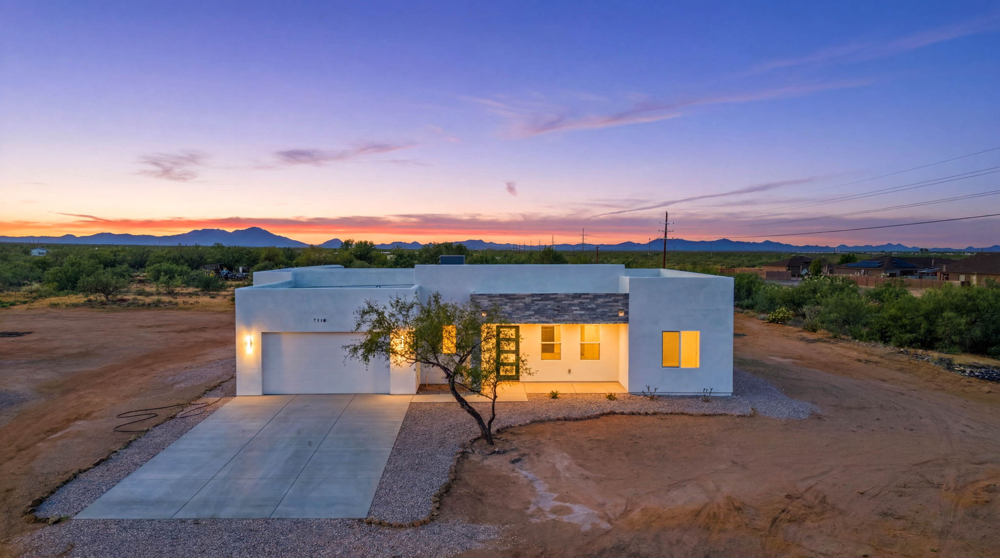 Modern single-story home on an open desert lot at dusk